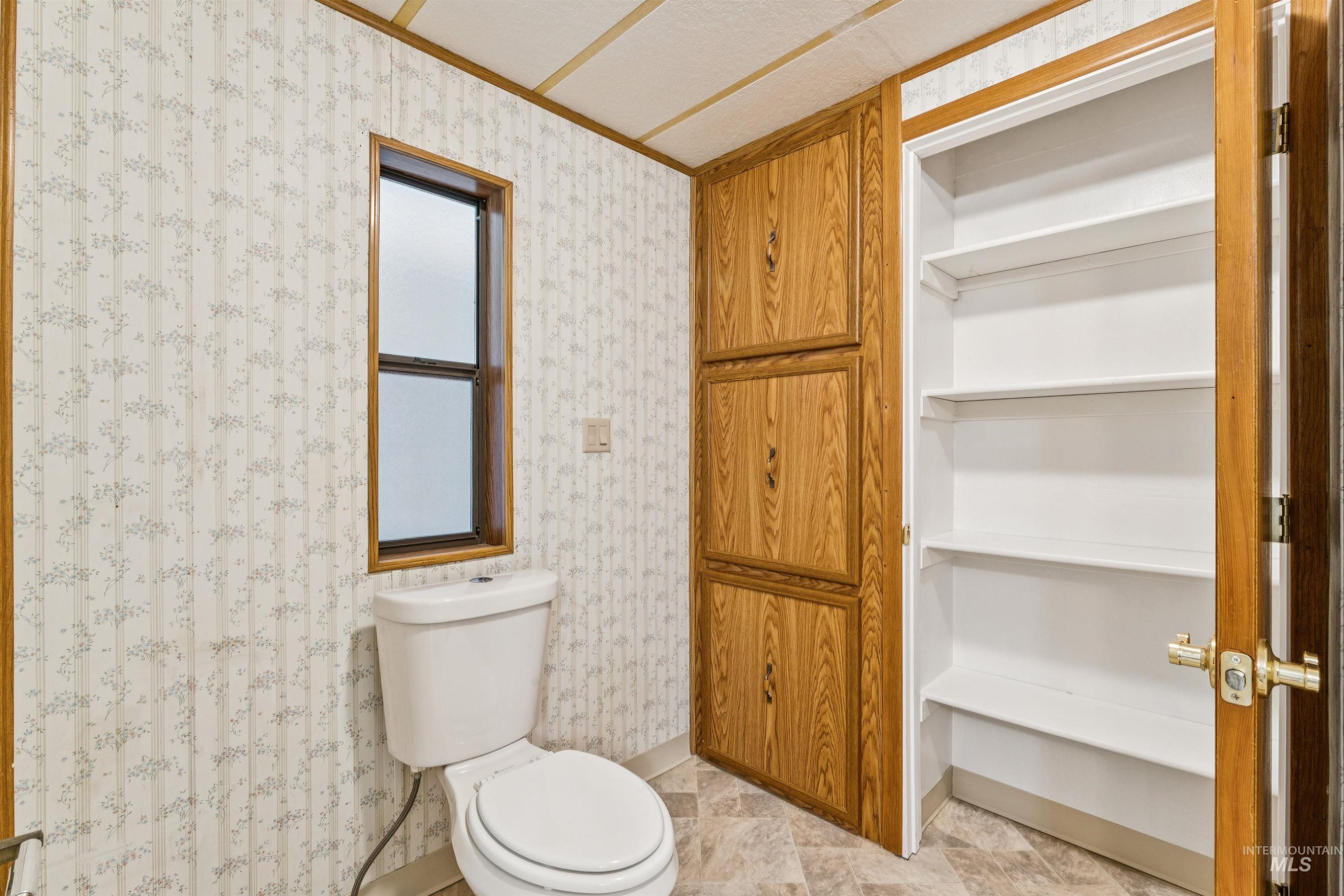Full bathroom with toilet and wallpapered walls
