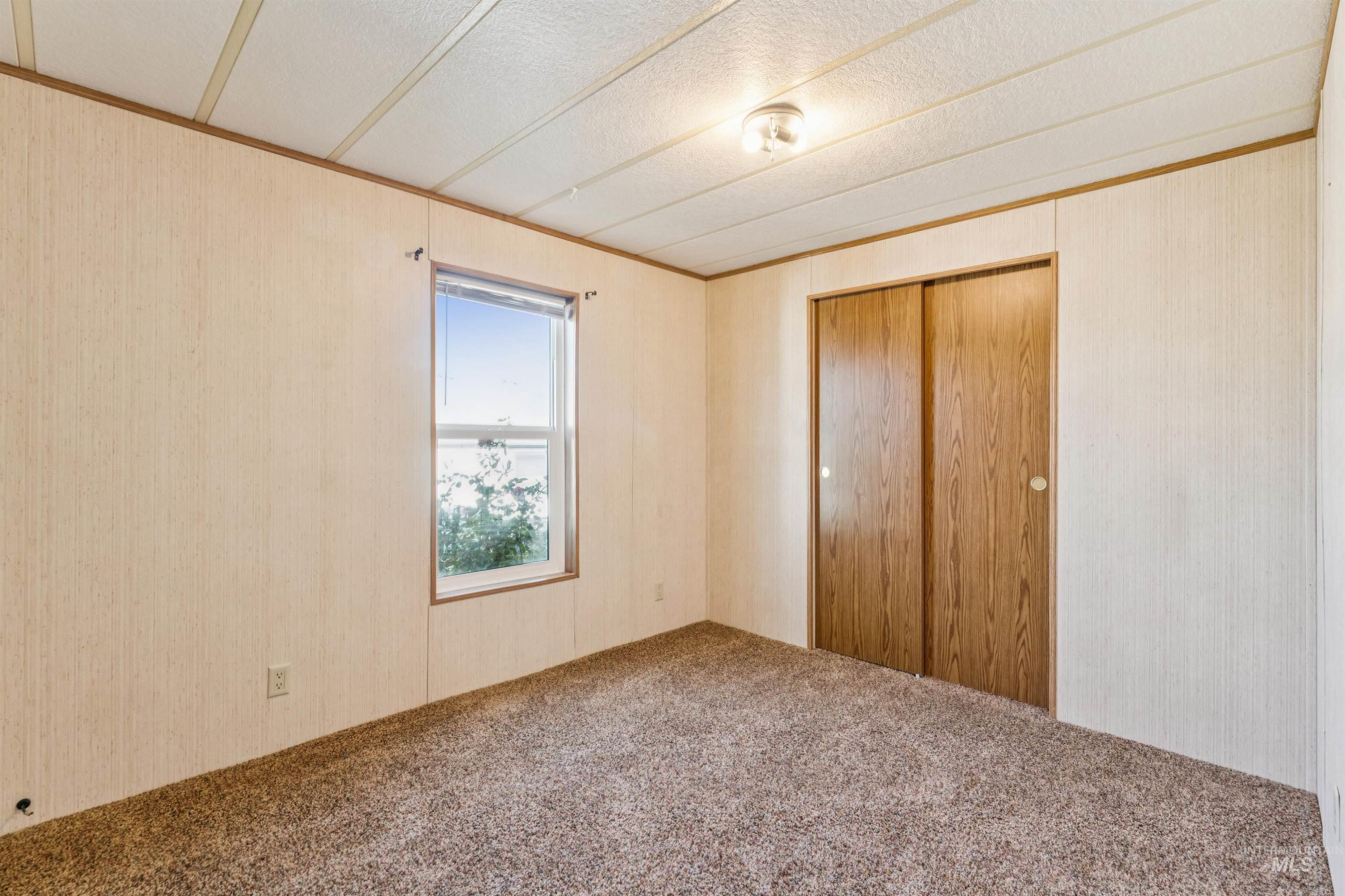 Unfurnished bedroom with carpet flooring, a closet, crown molding, a textured ceiling, and wallpapered walls