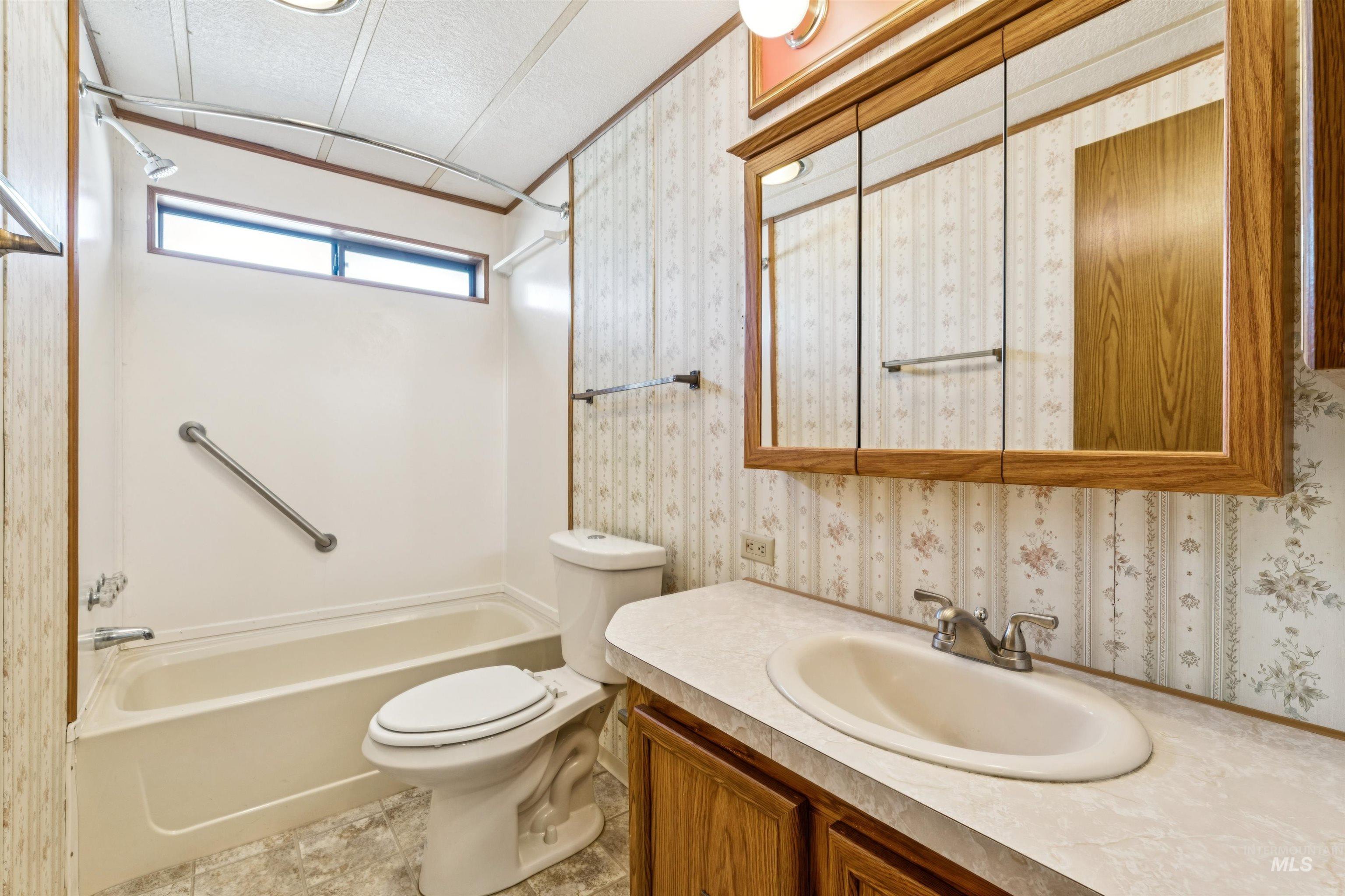 Full bathroom featuring shower / bathtub combination, vanity, wallpapered walls, and a textured ceiling