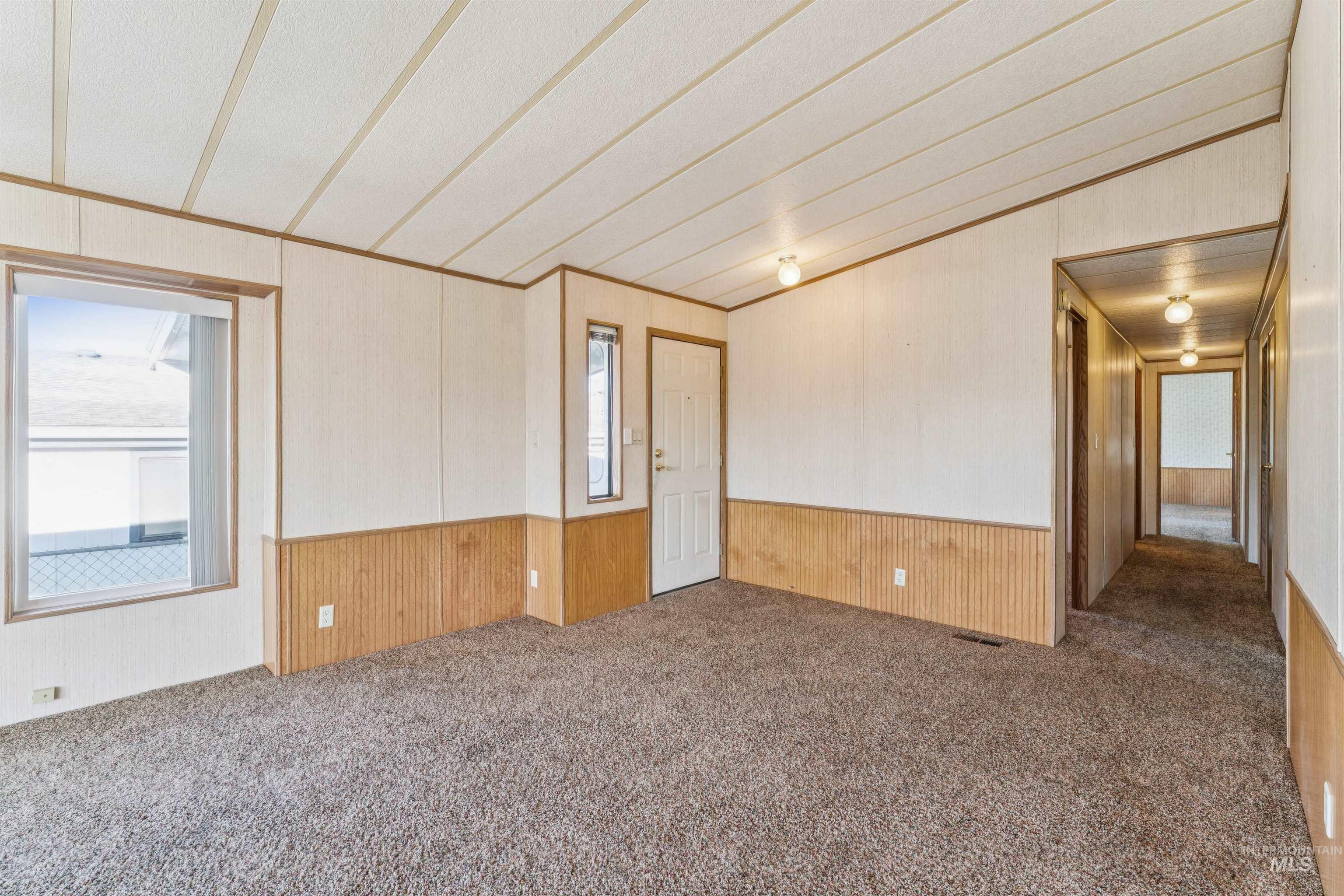 Carpeted spare room with wooden walls, a wainscoted wall, and crown molding