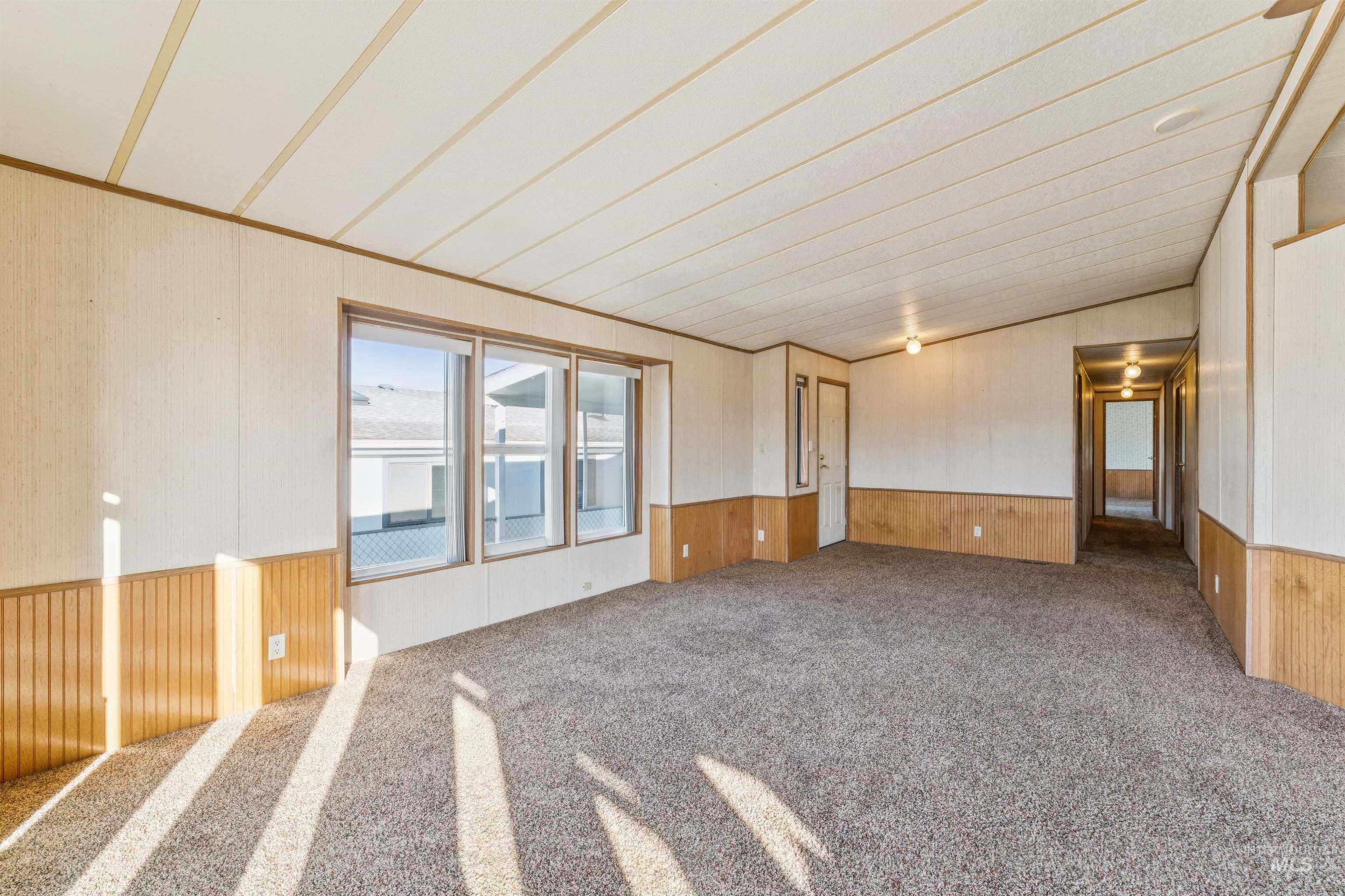 Carpeted spare room featuring wood walls and a wainscoted wall