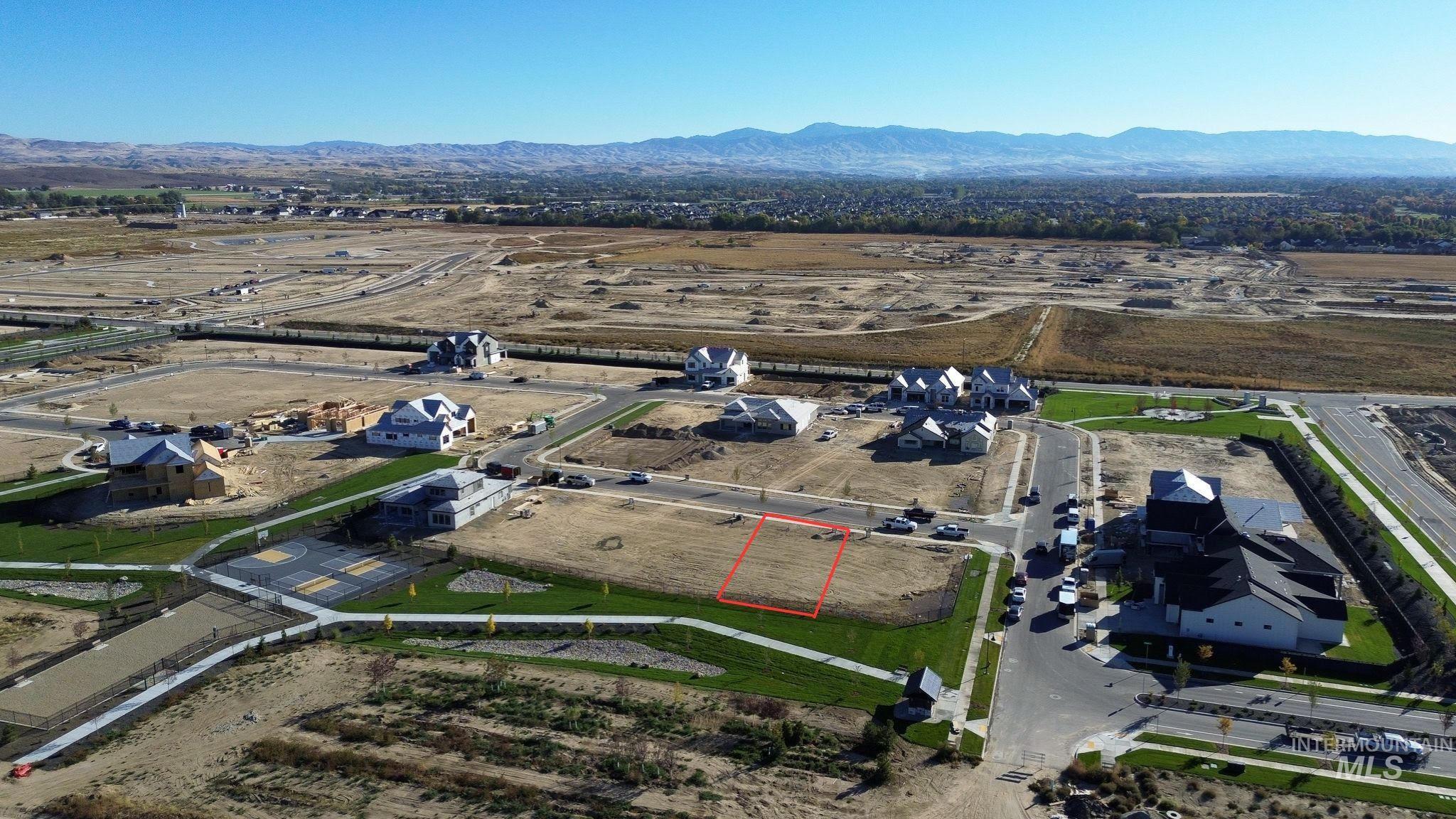 Aerial view of property's location featuring property parcel outlined, a mountainous background, and nearby suburban area