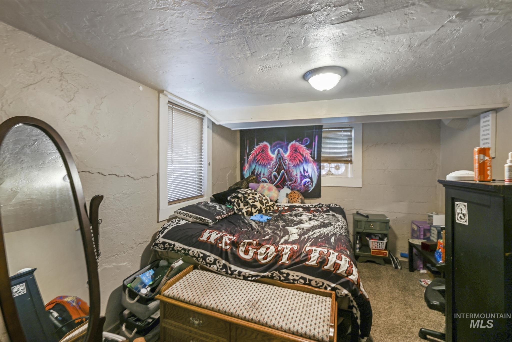 Bedroom with a textured ceiling, a textured wall, and concrete block wall