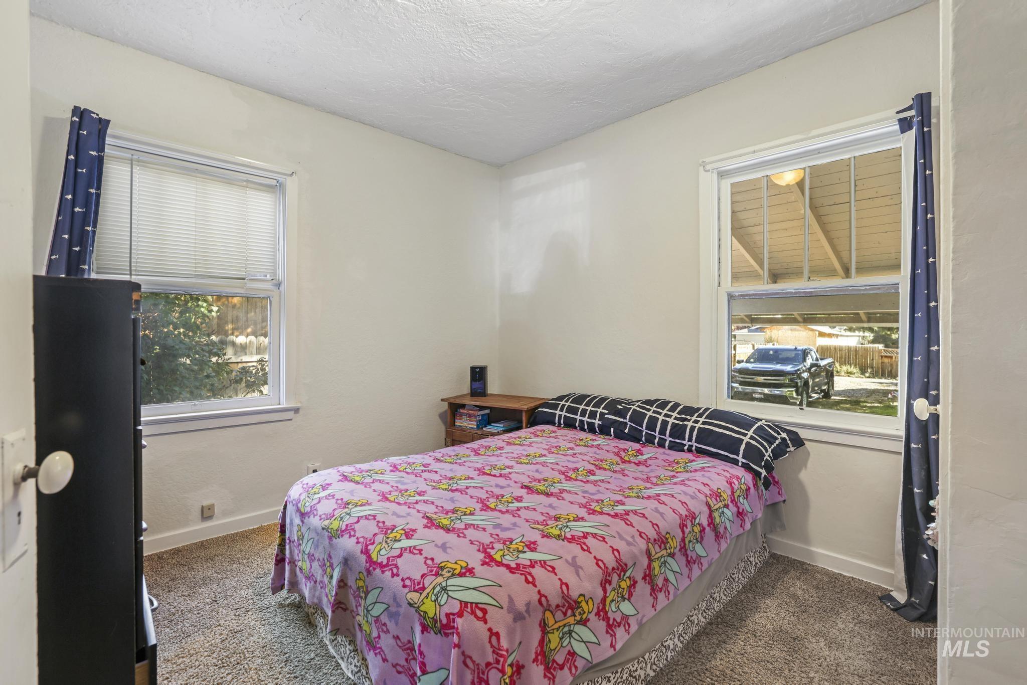 Bedroom featuring multiple windows, dark colored carpet, and a textured ceiling