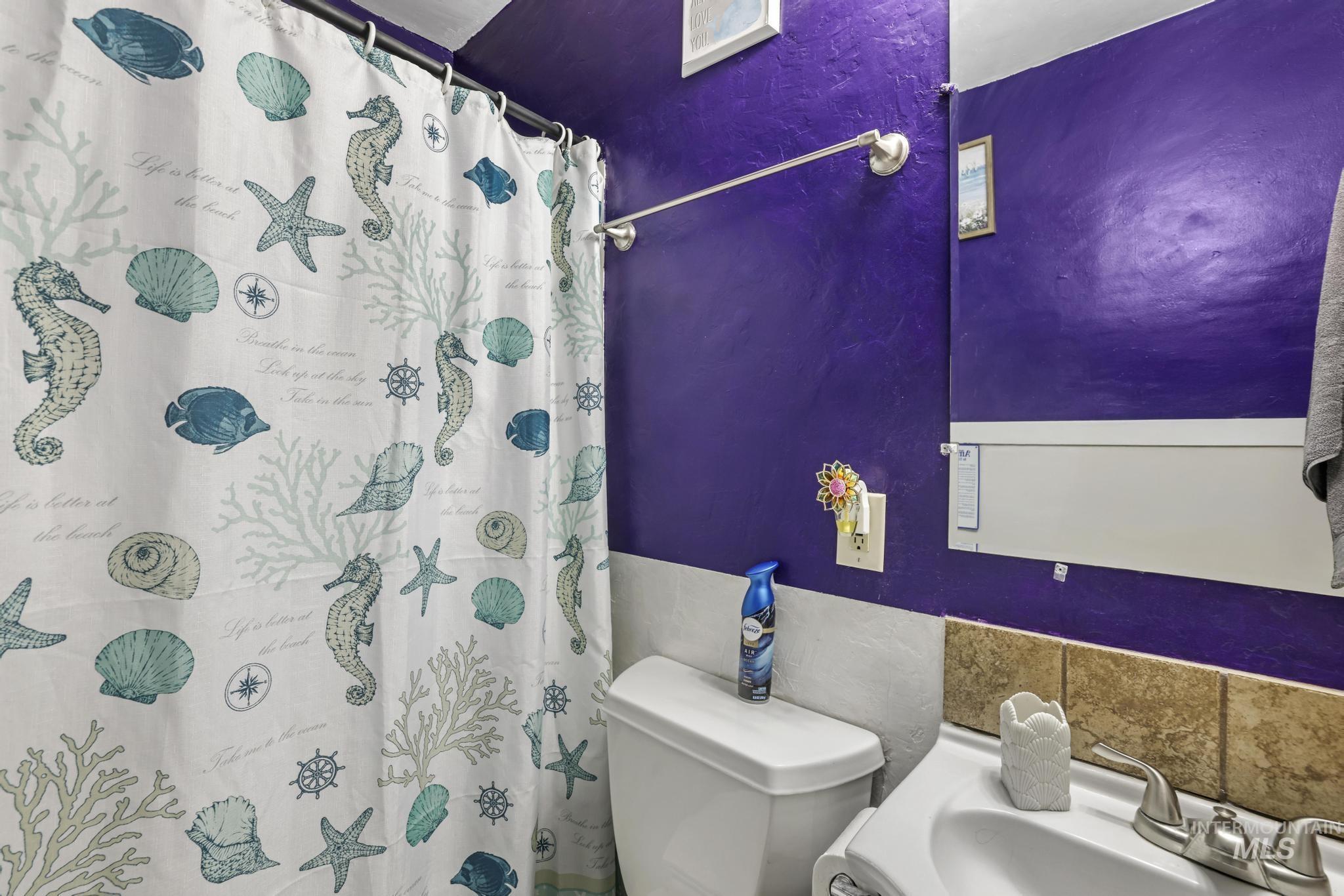 Bathroom featuring a shower with shower curtain, vanity, and decorative backsplash