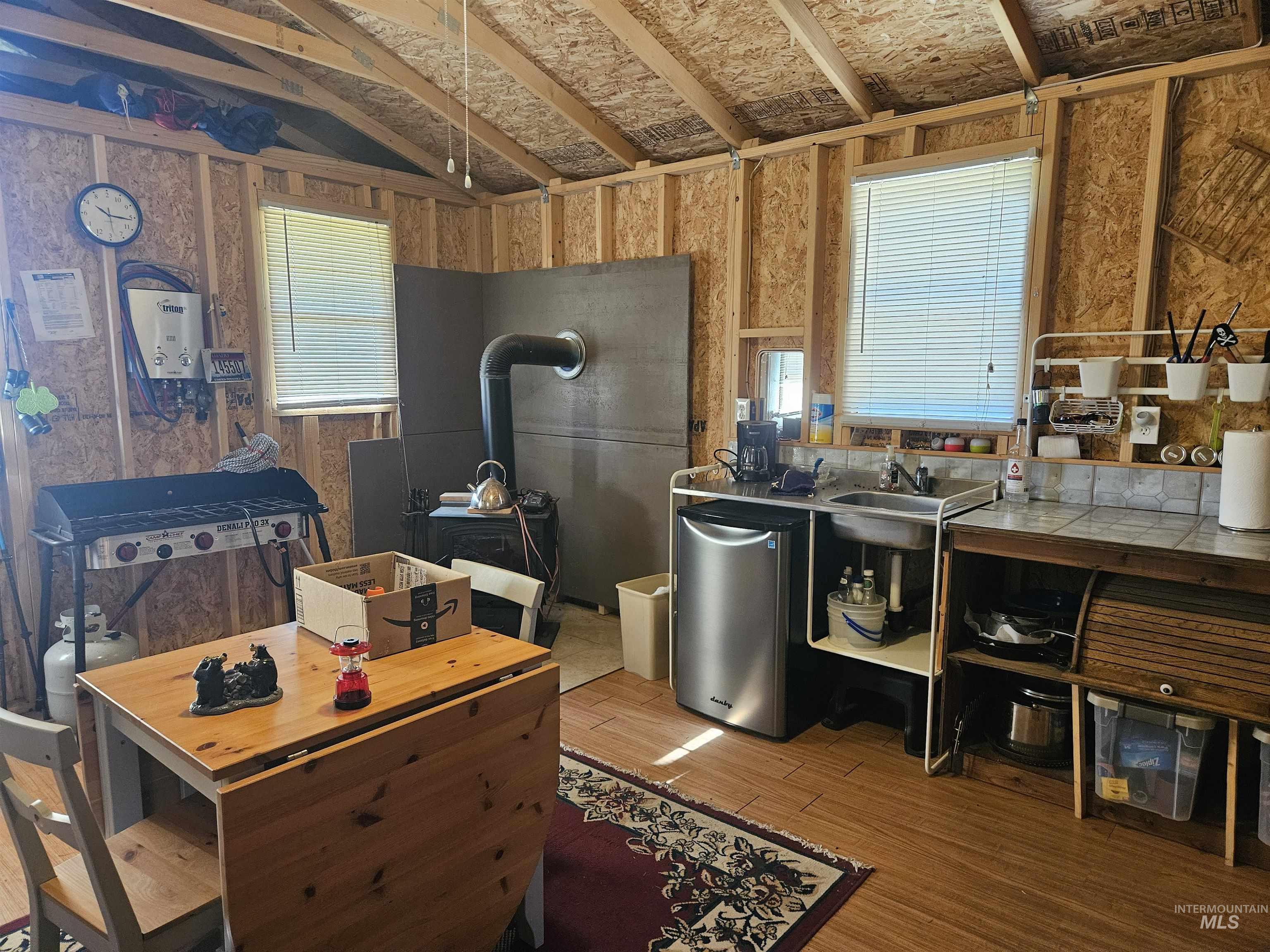 Kitchen with wood finished floors, vaulted ceiling, and a wood stove