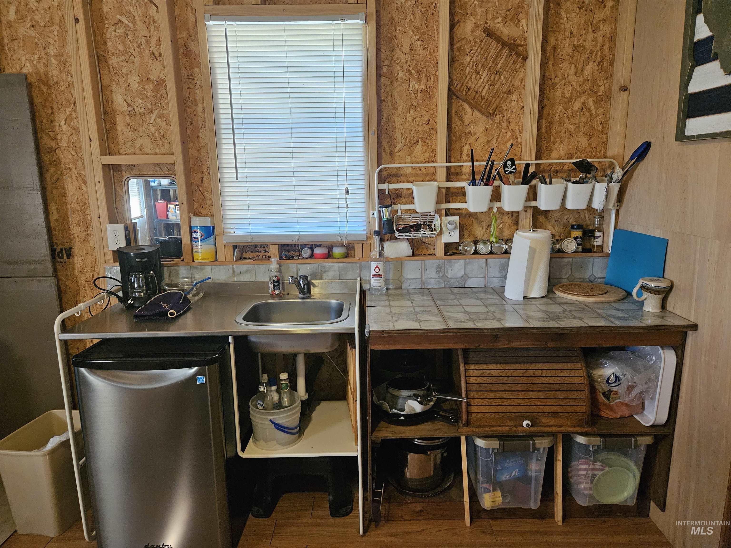 Kitchen featuring wood finished floors, tile countertops, and freestanding refrigerator