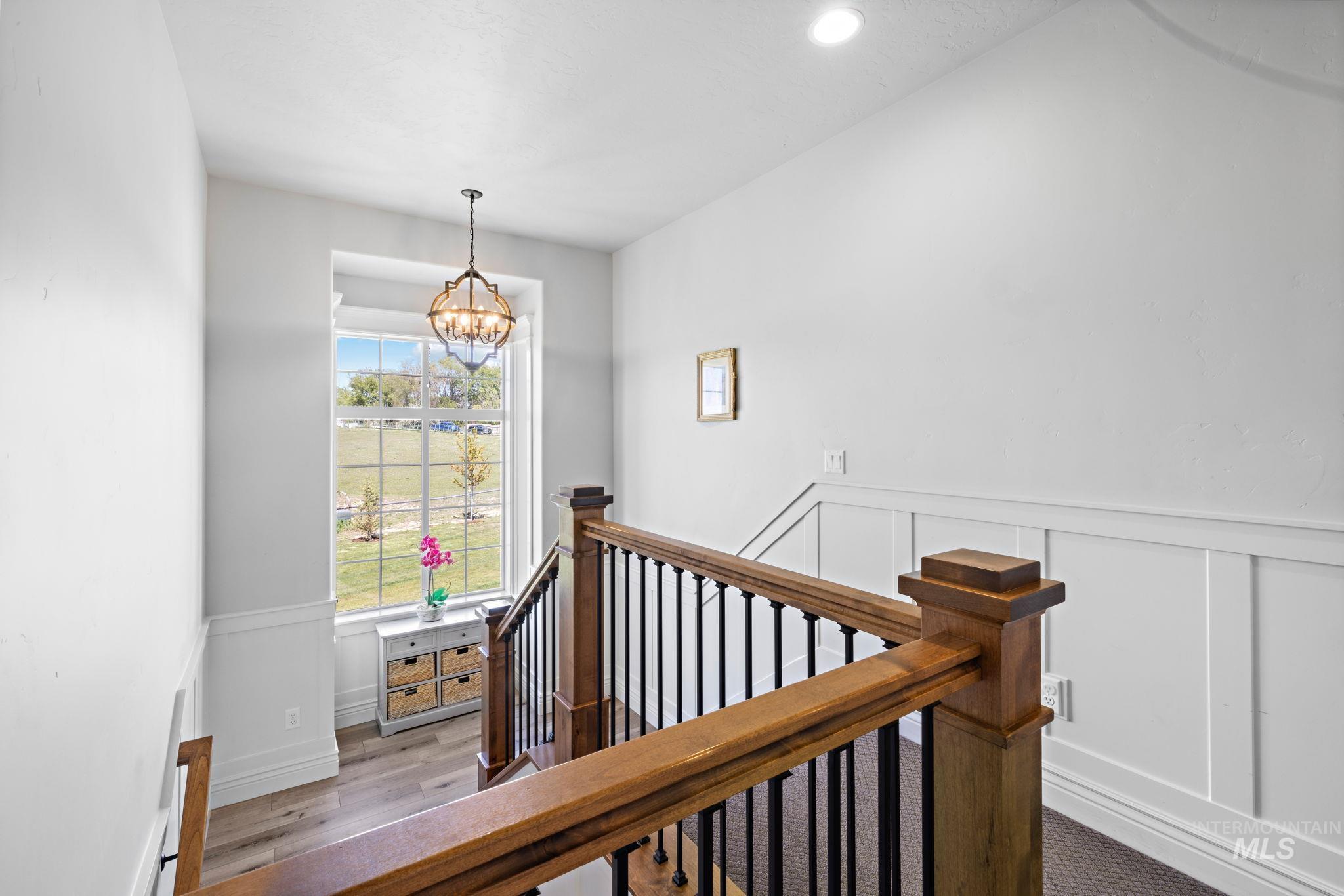 Stairs featuring wainscoting, a decorative wall, a chandelier, wood finished floors, and recessed lighting