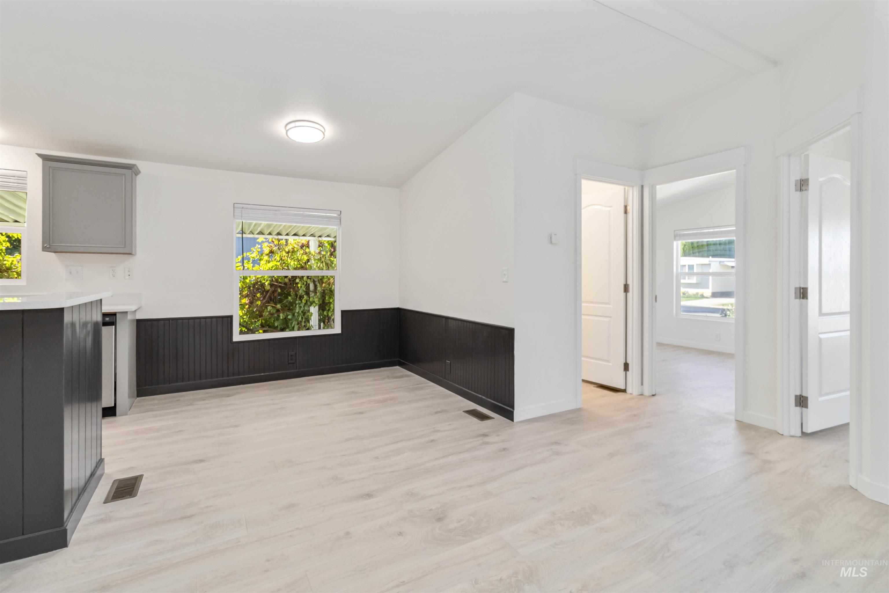 Empty room with light wood-style floors and a wainscoted wall