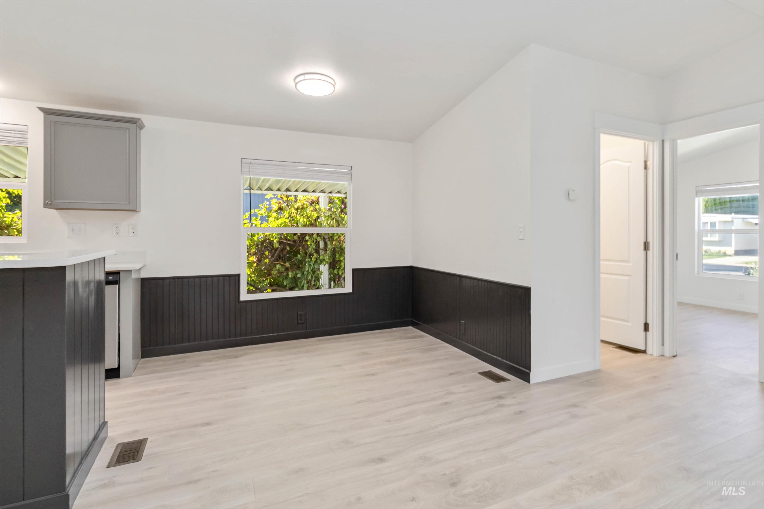 Unfurnished dining area featuring light wood-style floors and a wainscoted wall