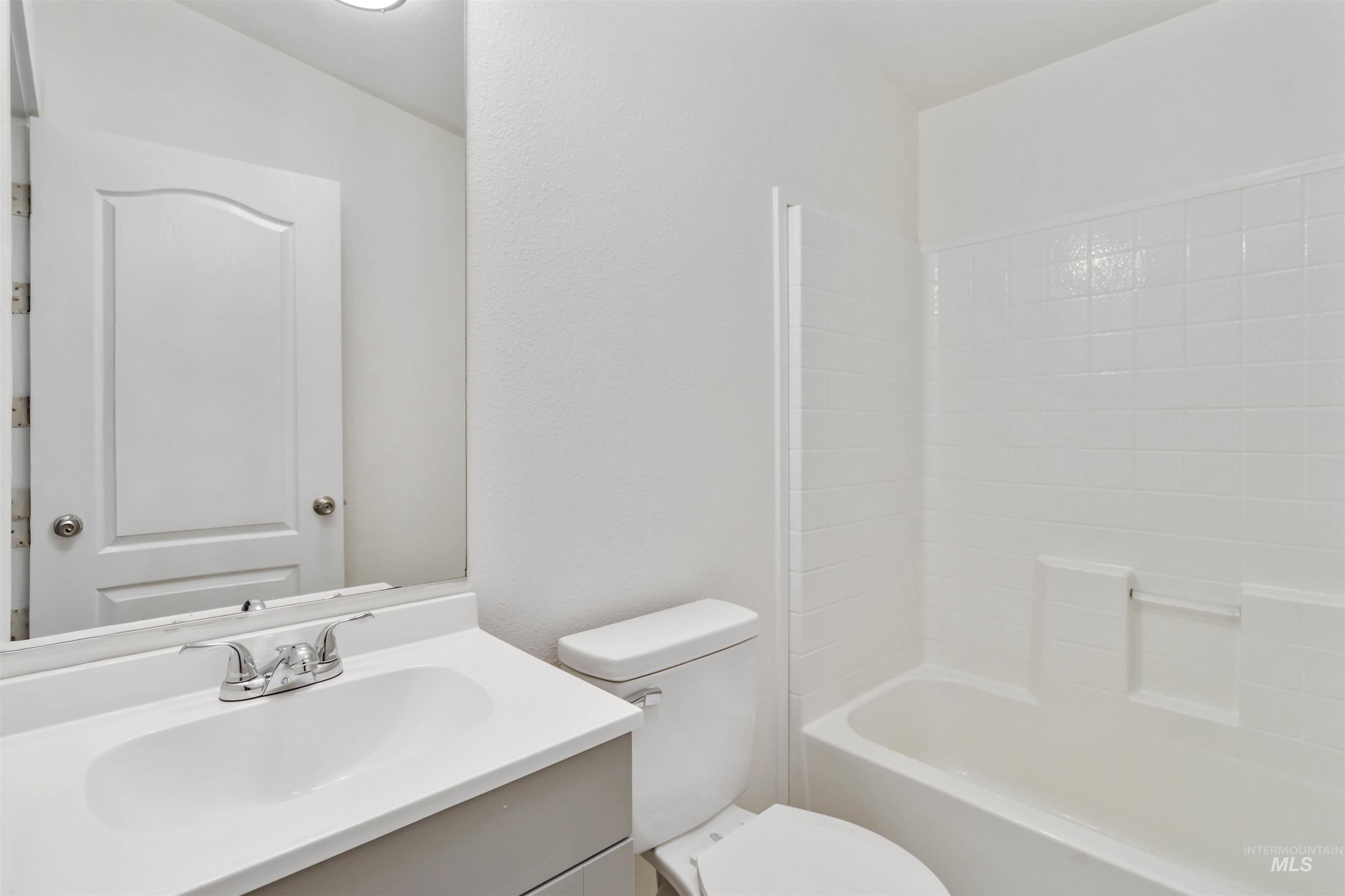 Bathroom with vanity, washtub / shower combination, and a textured wall