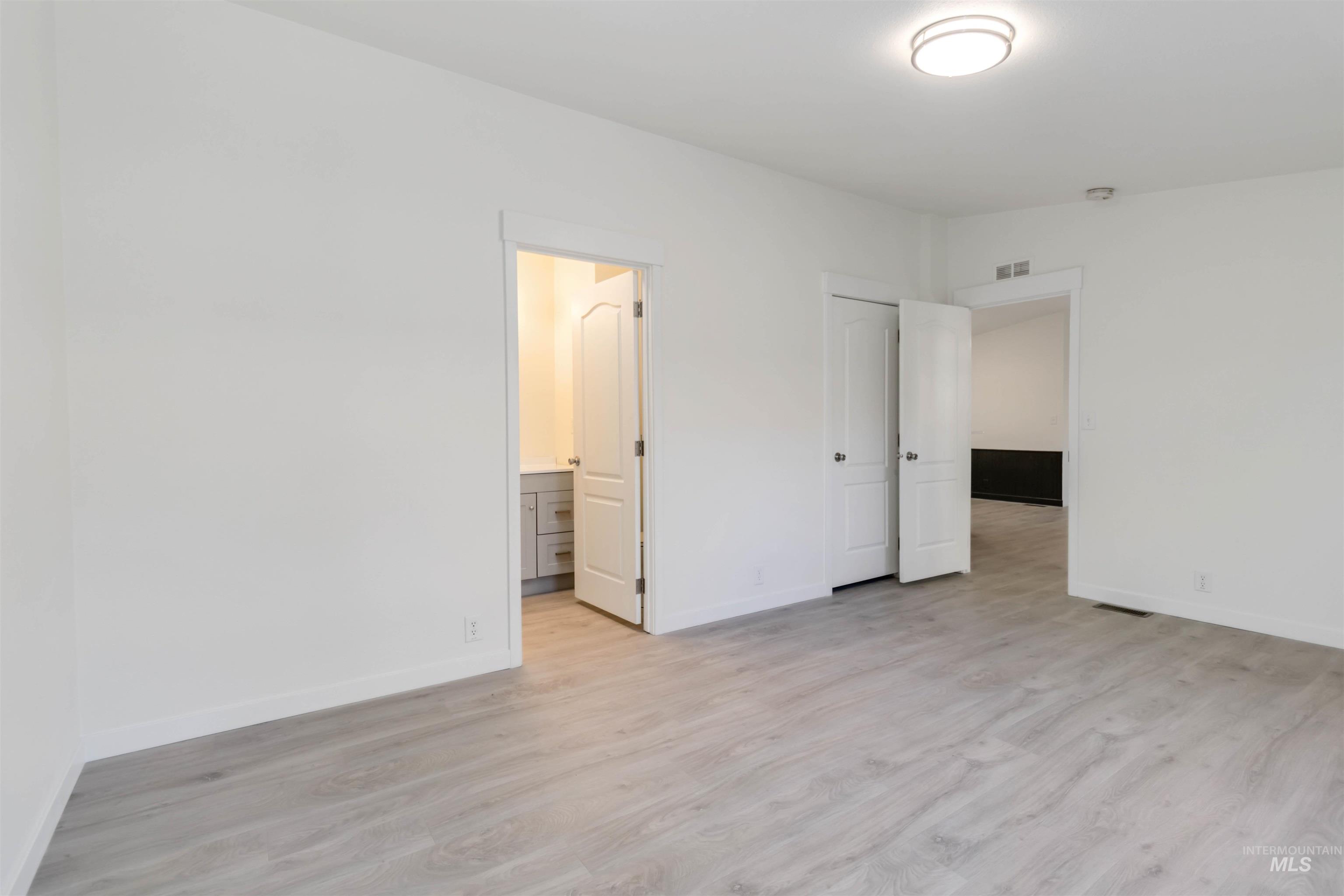 Unfurnished bedroom featuring light wood-style floors and ensuite bath