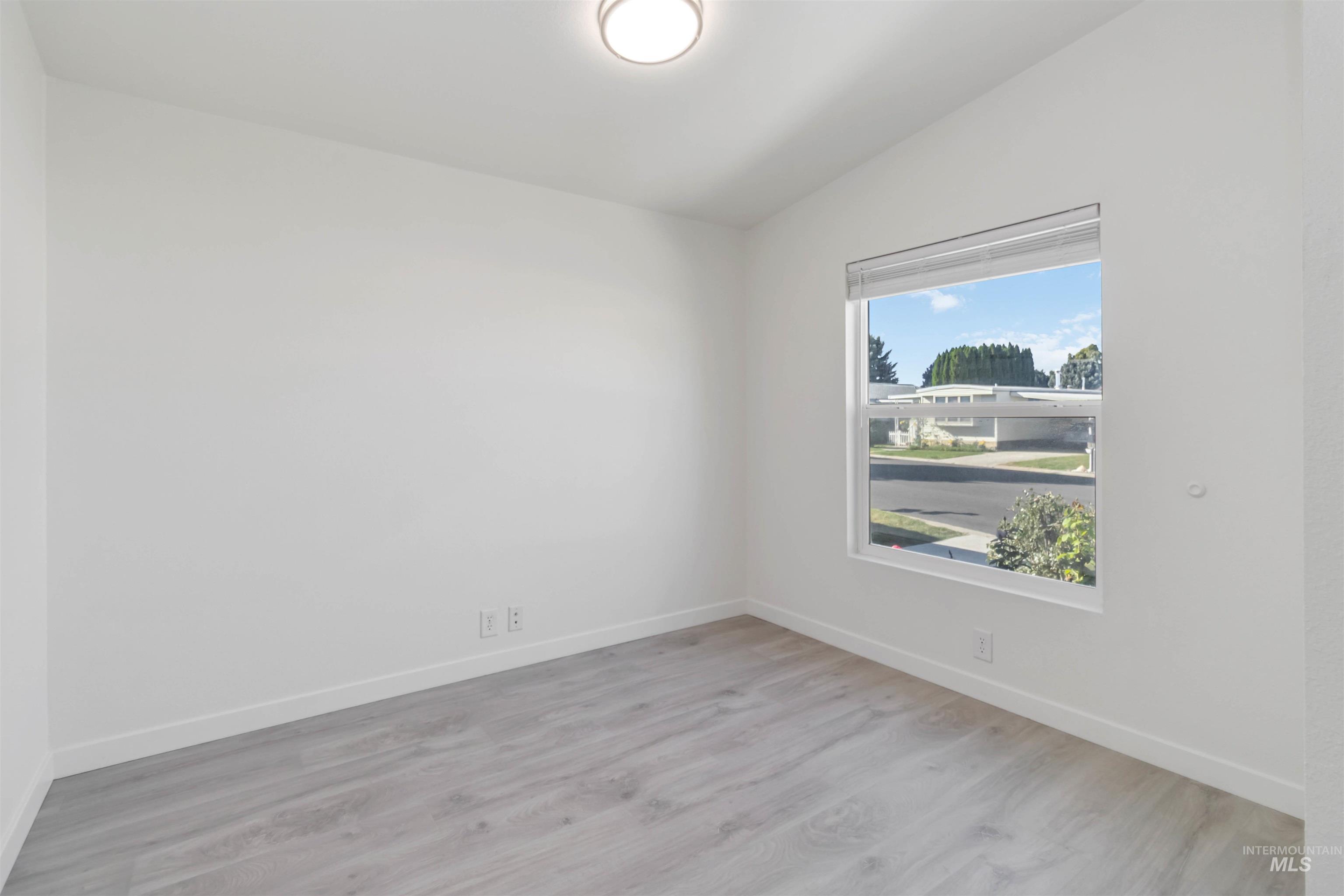 Unfurnished room featuring light wood-style flooring and lofted ceiling