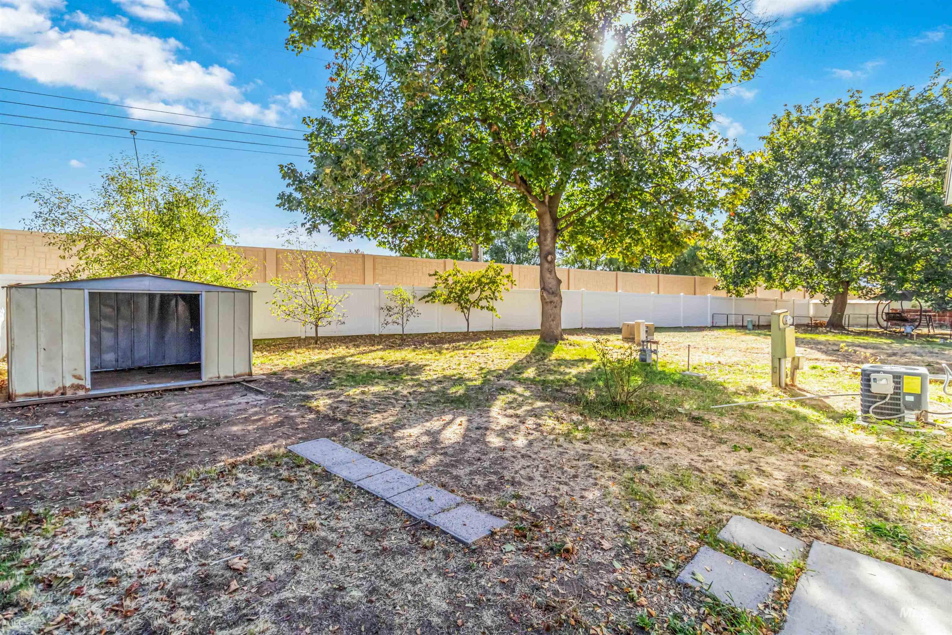 Fenced backyard featuring a storage unit
