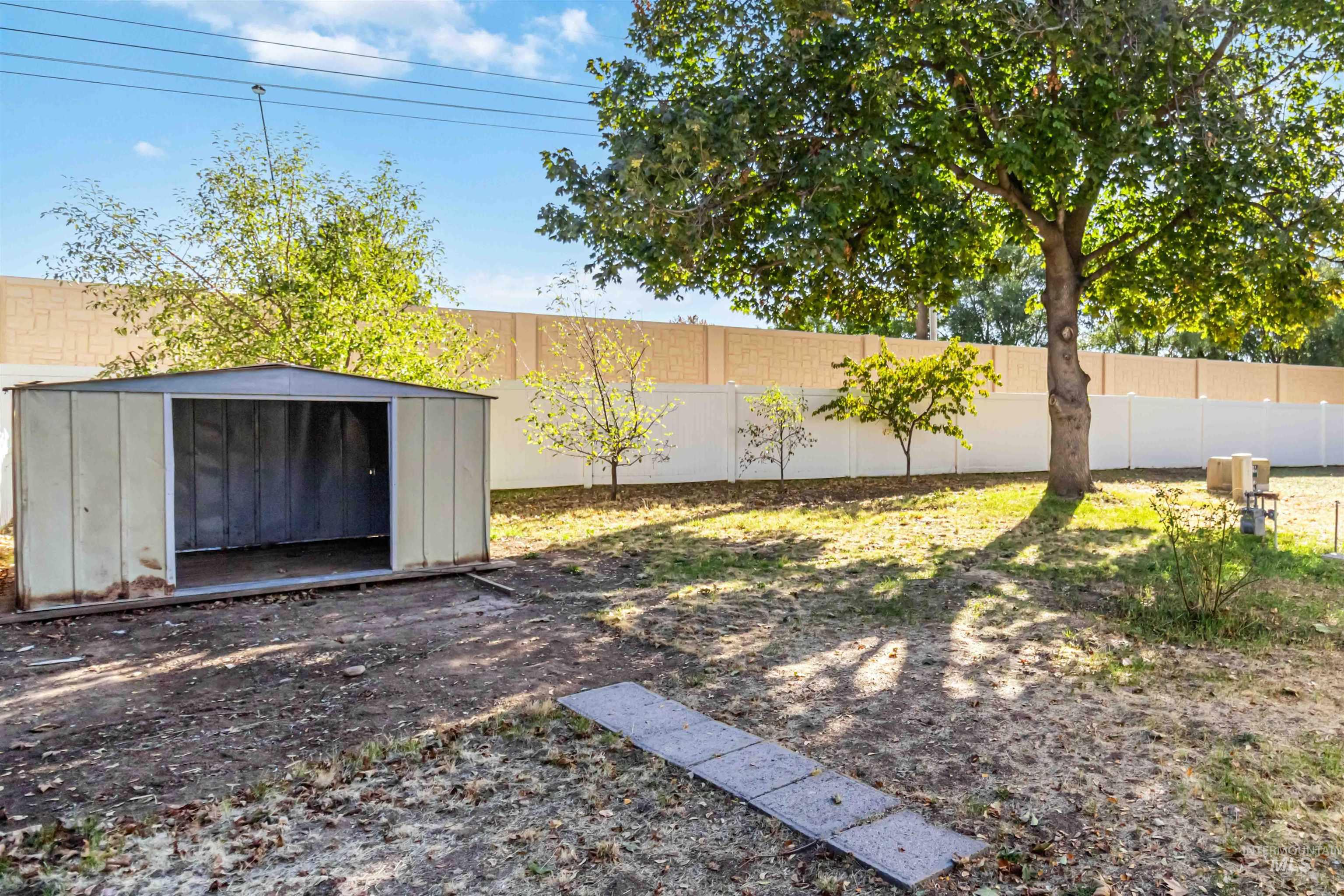 Fenced backyard featuring a storage shed