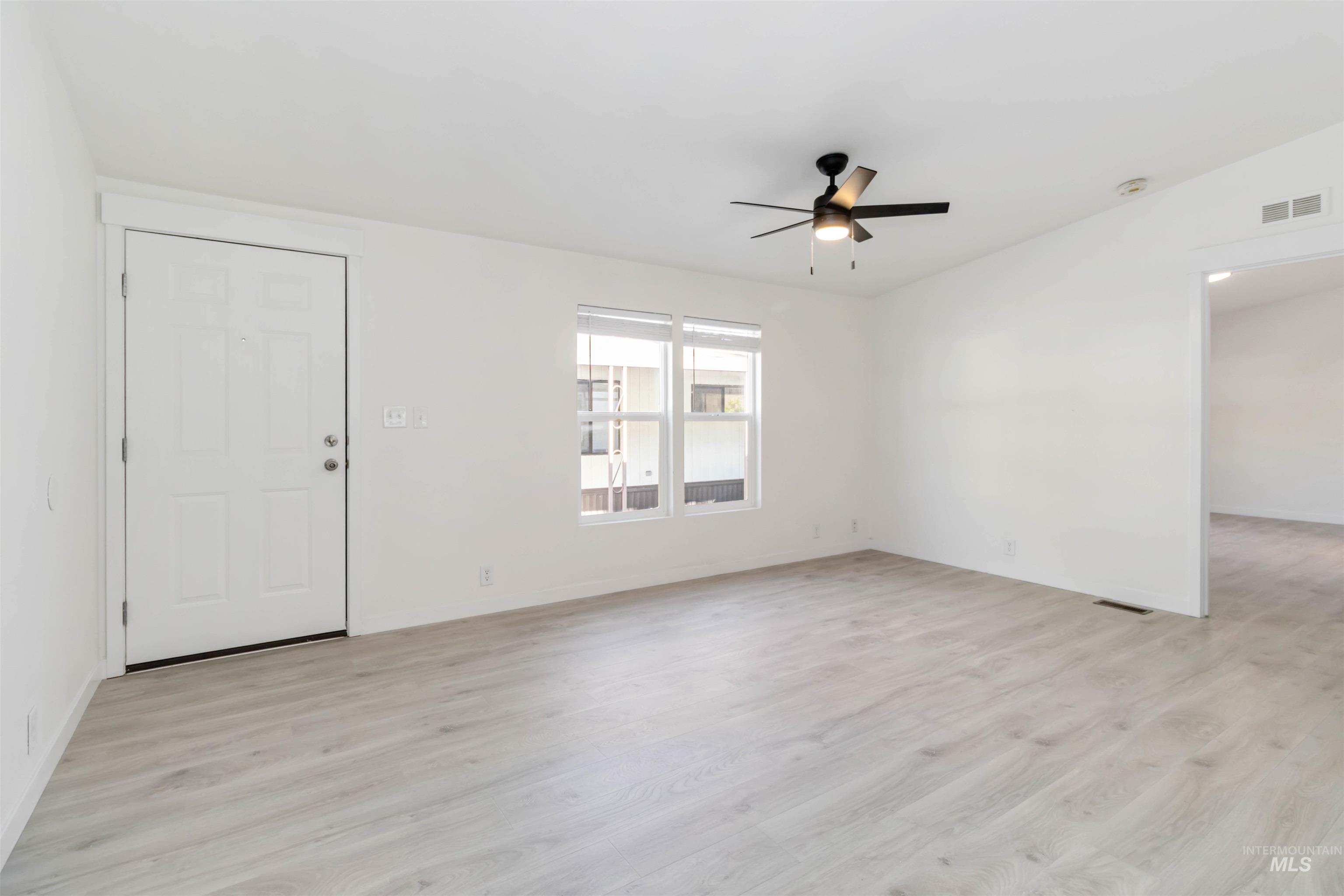 Unfurnished living room with light wood-style floors and a ceiling fan