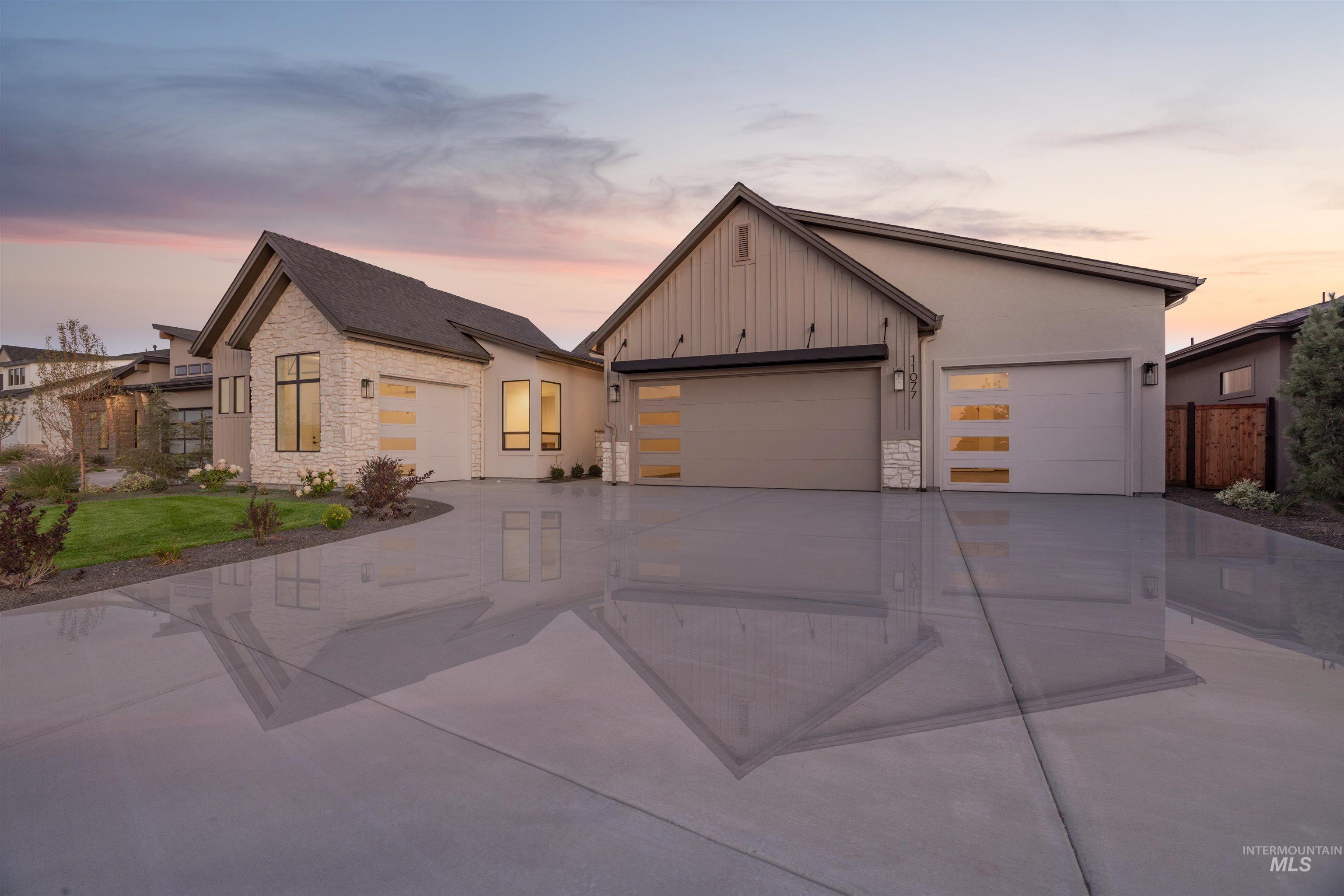 View of front facade featuring stone siding, concrete driveway, board and batten siding, and an attached garage