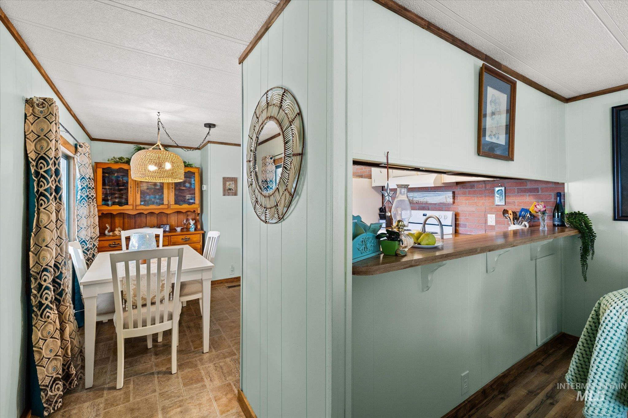 Kitchen with crown molding, a textured ceiling, butcher block countertops, stove, and white cabinetry