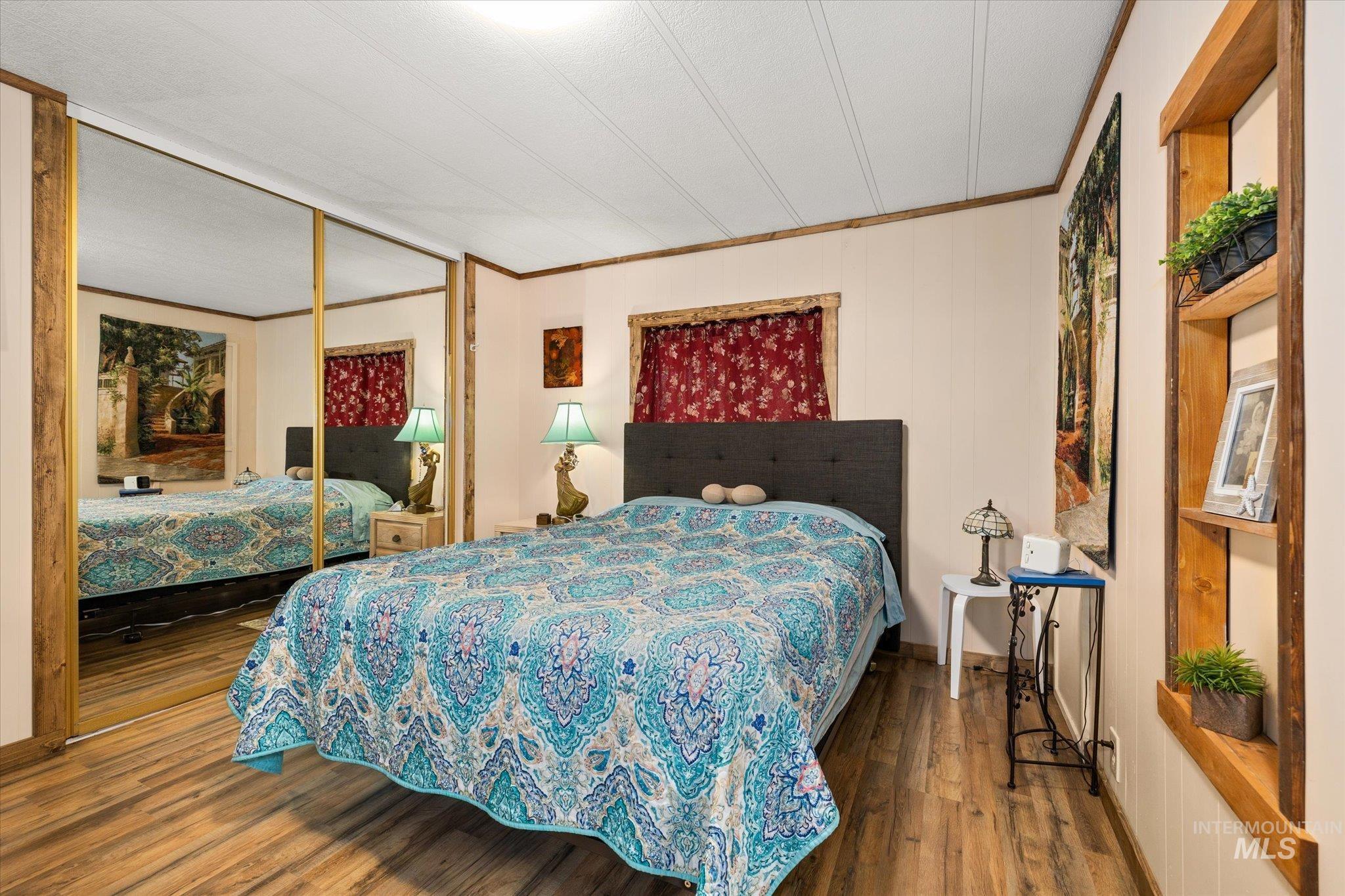 Bedroom with crown molding, wood finished floors, and a closet