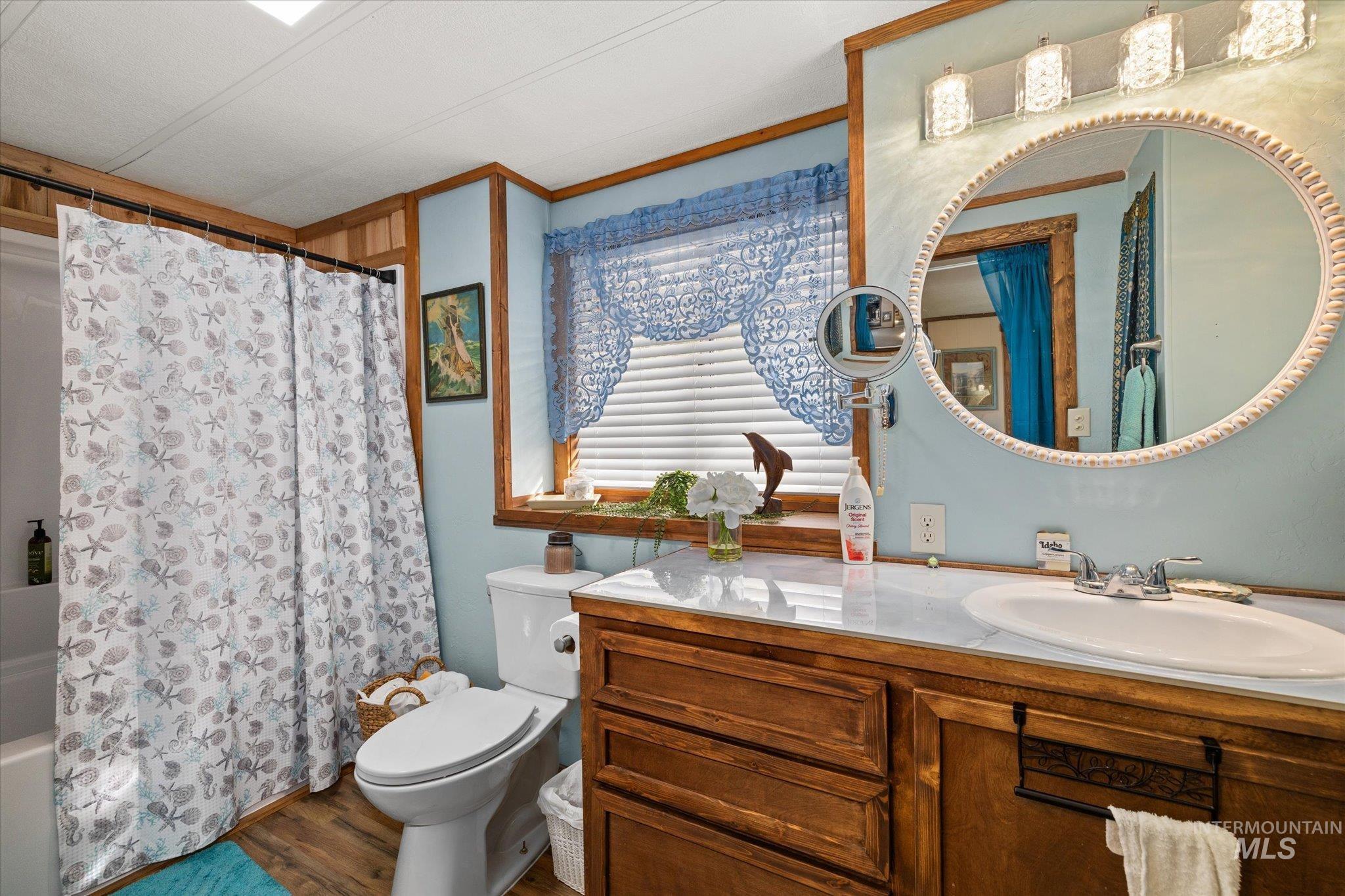 Full bath featuring shower / bathtub combination with curtain, vanity, wood finished floors, and ornamental molding