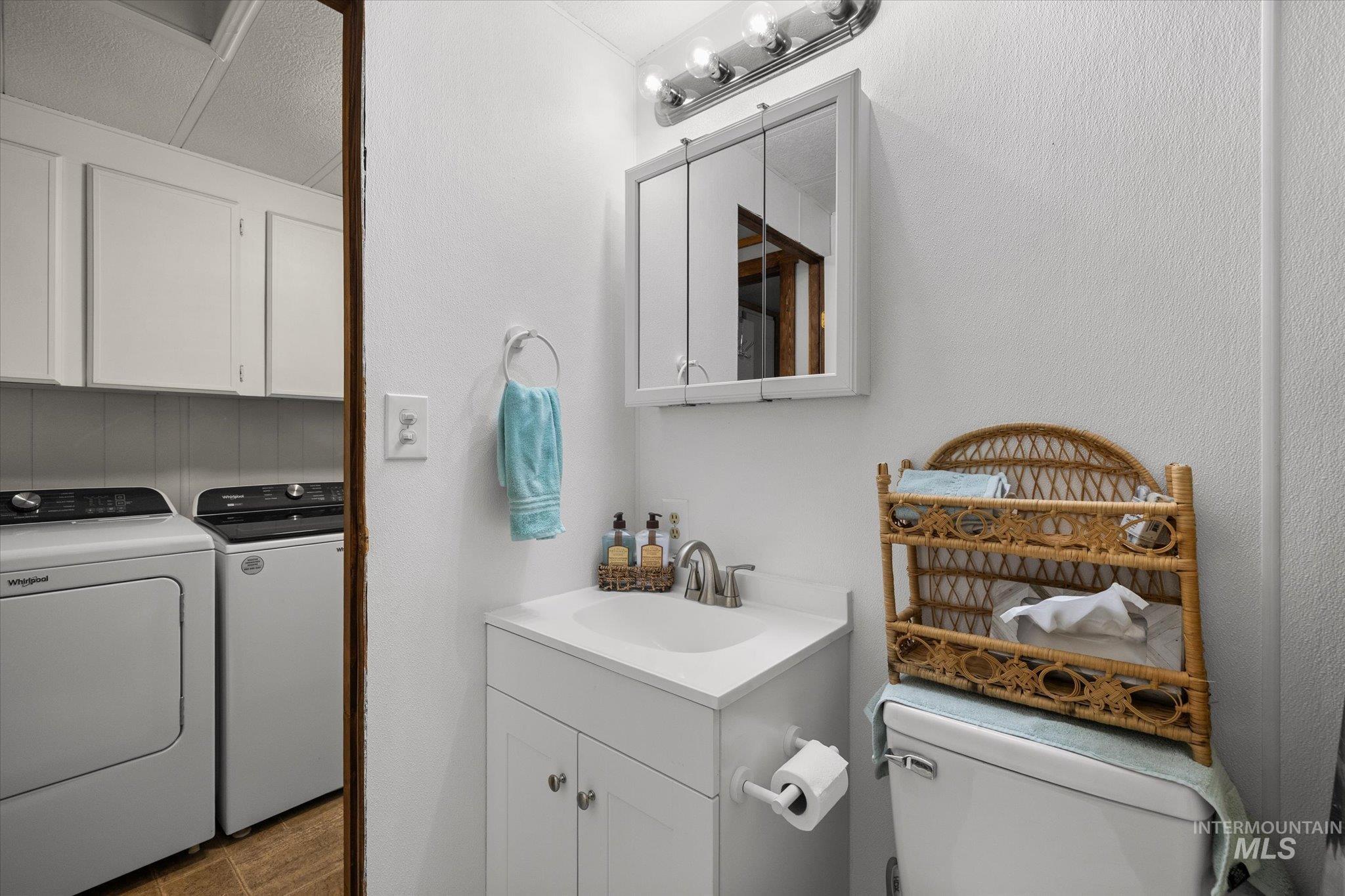 Half bath featuring vanity and washing machine and clothes dryer