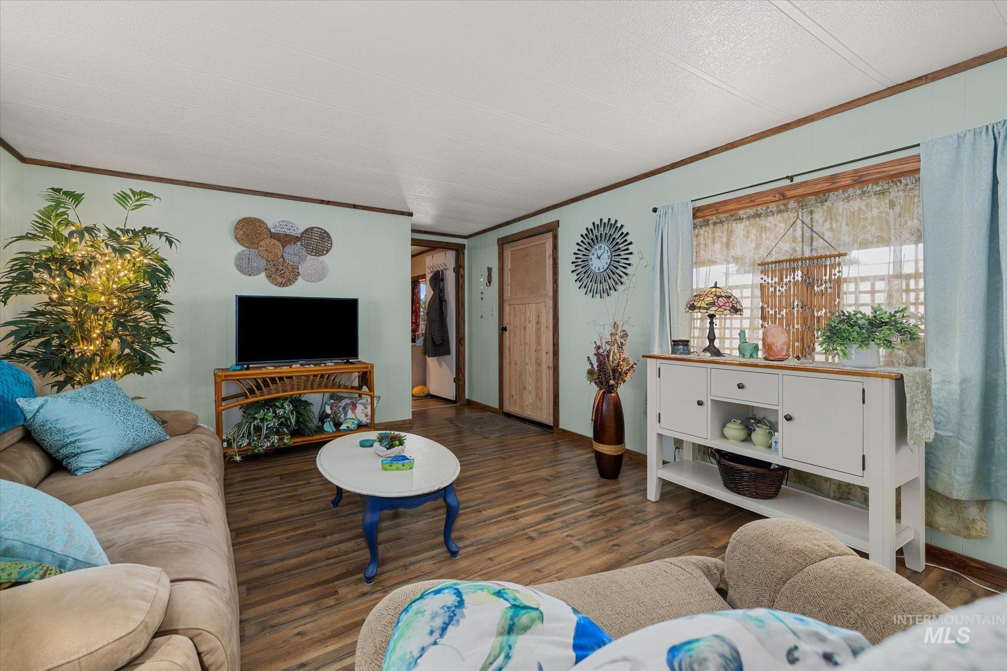 Living area with crown molding and wood finished floors