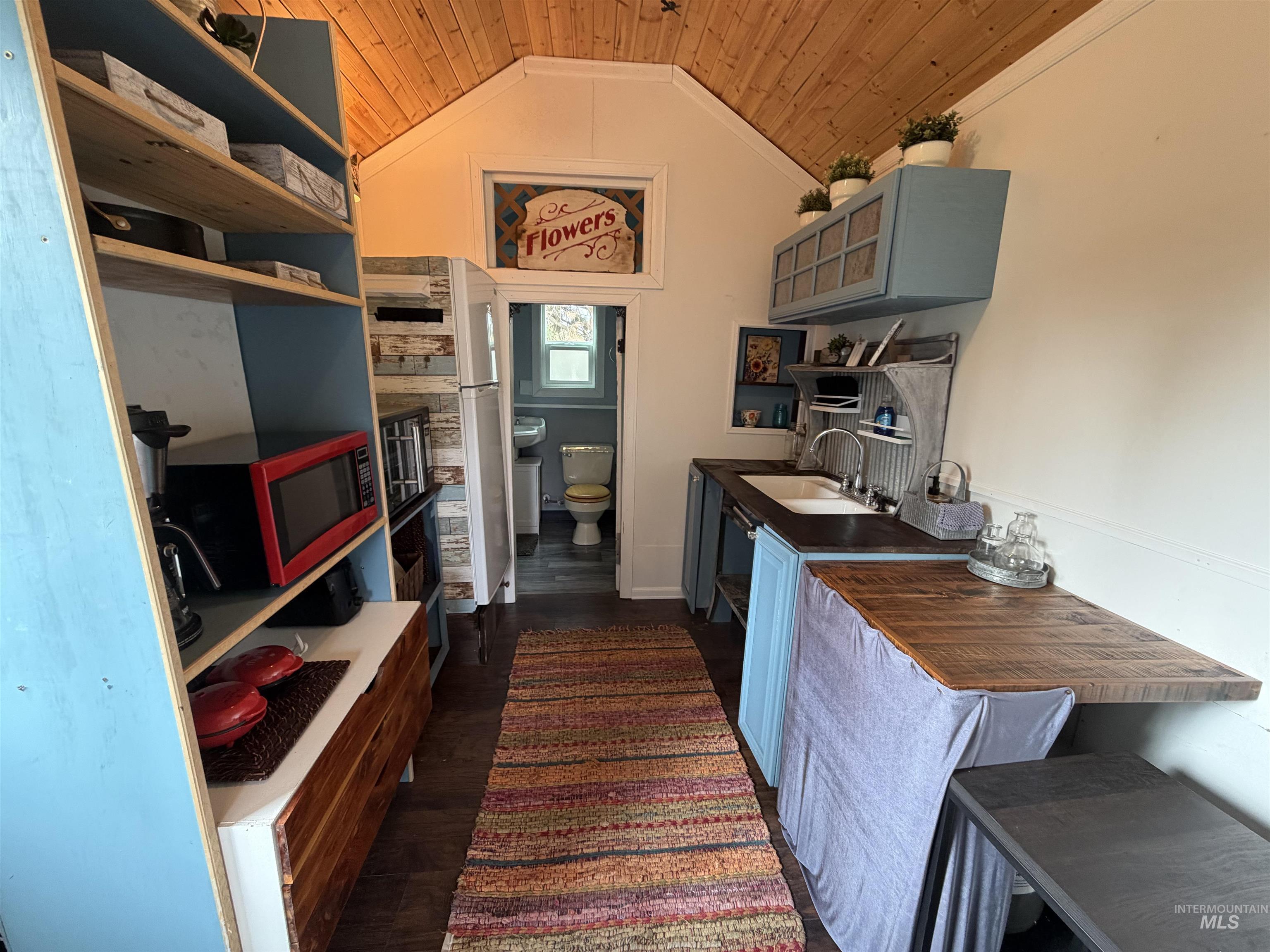 Kitchen featuring dark wood-style flooring, wood ceiling, vaulted ceiling, blue cabinetry, and open shelves