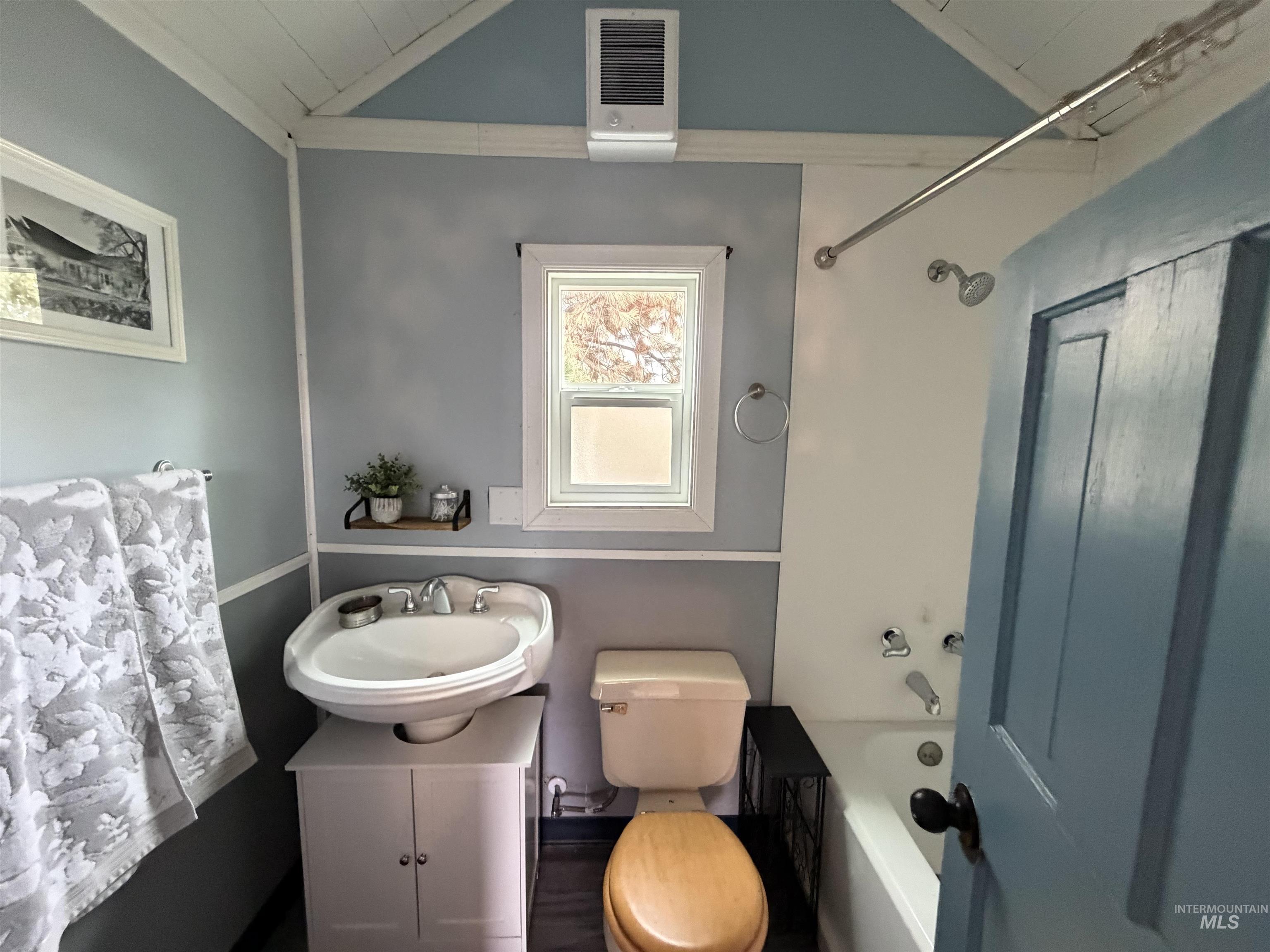 Bathroom with vanity, bathing tub / shower combination, and vaulted ceiling