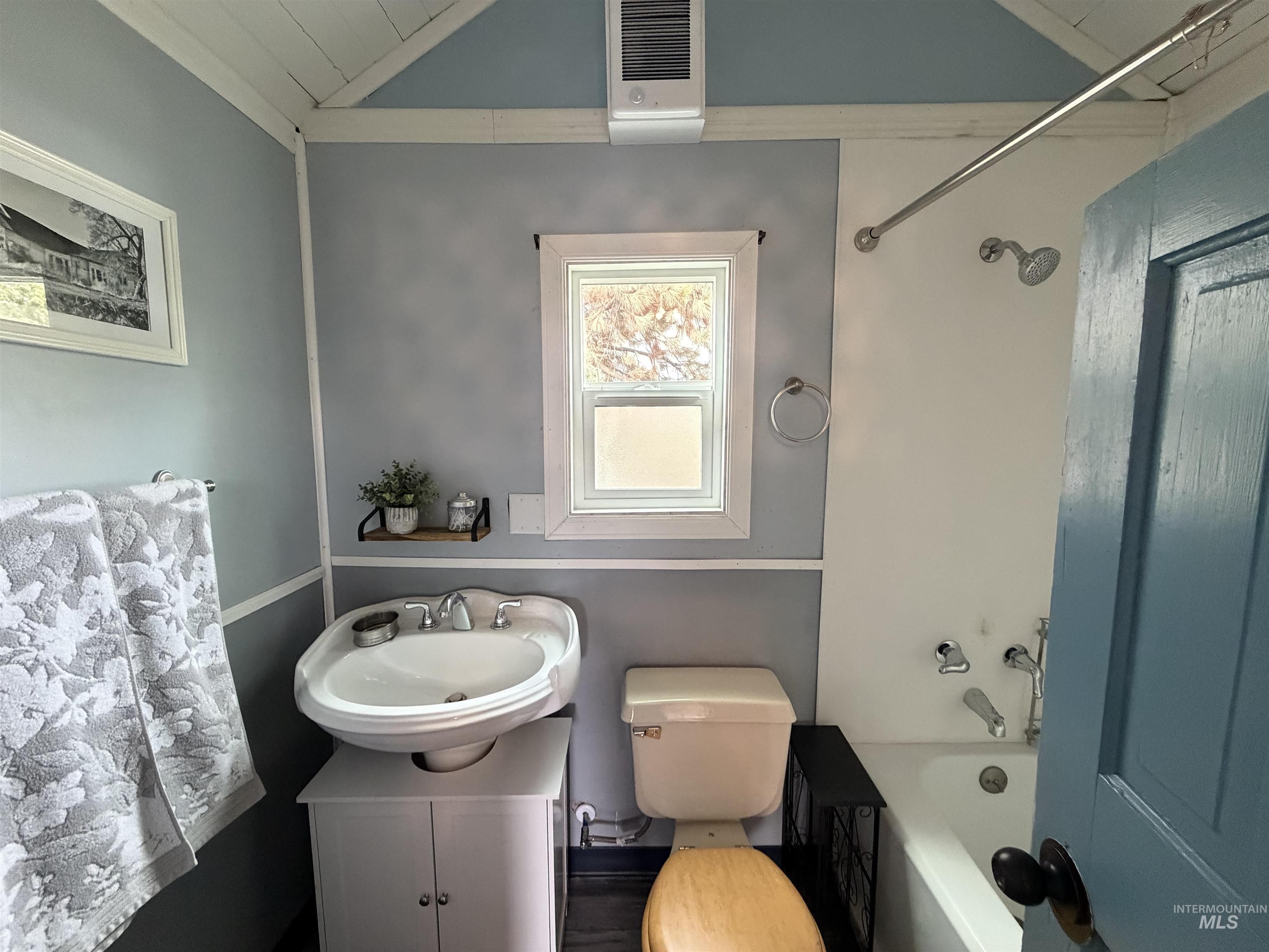 Bathroom with bathtub / shower combination, vanity, and vaulted ceiling