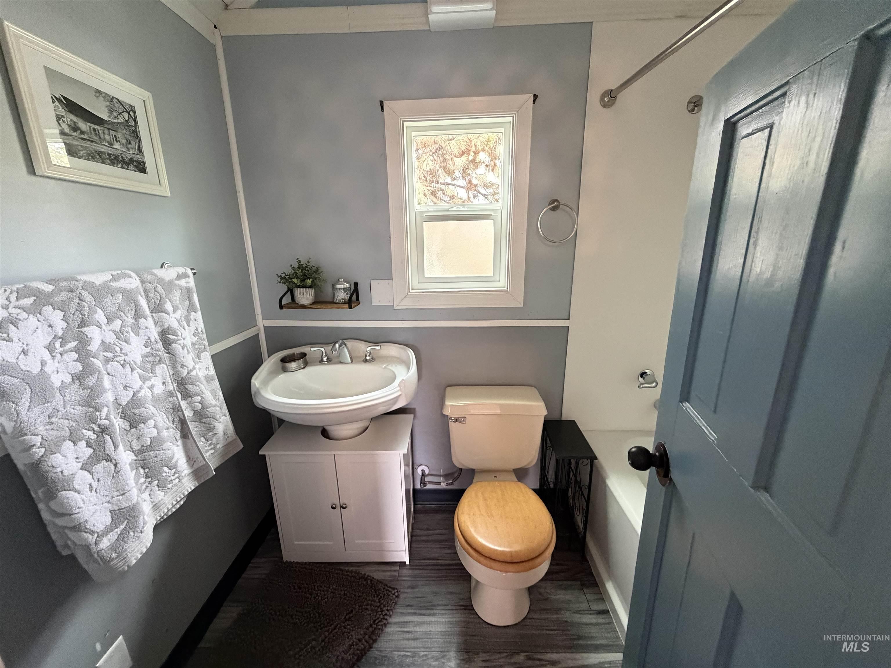 Bathroom featuring vanity, dark wood-style flooring, and a tub to relax in