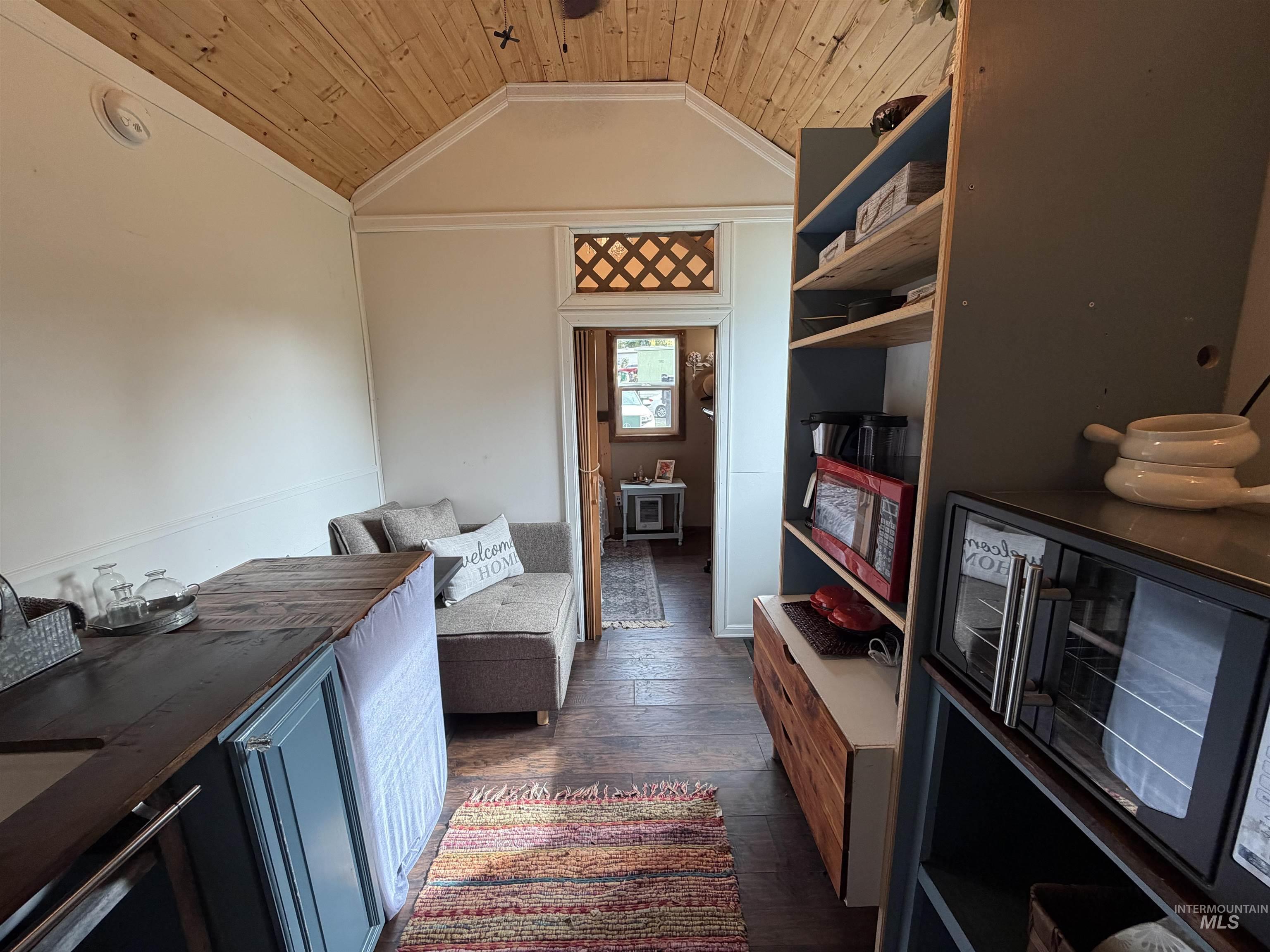 Living area with dark wood-style floors, wooden ceiling, and lofted ceiling