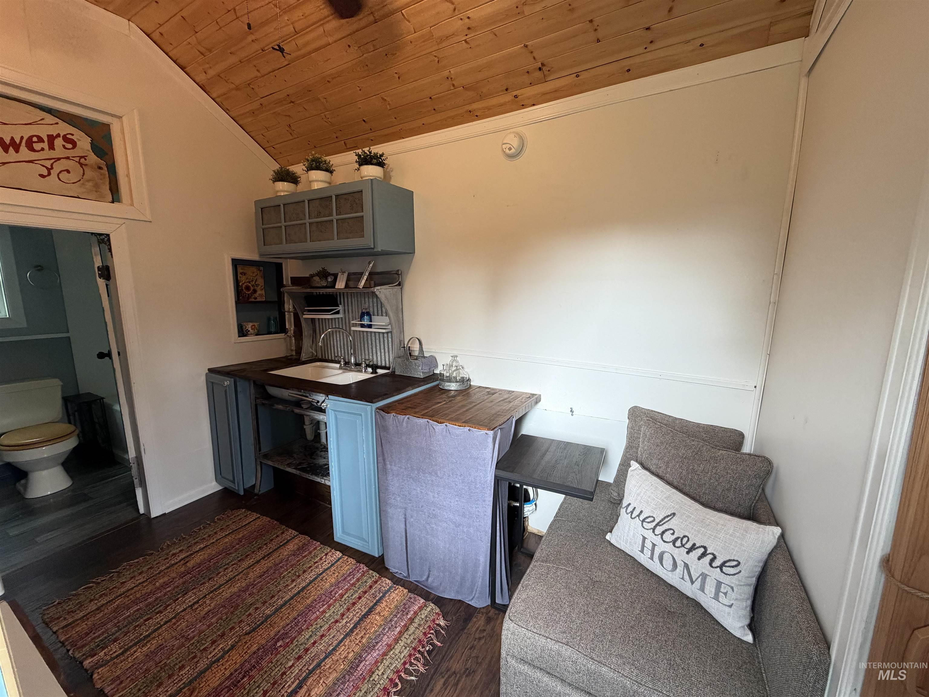 Kitchen featuring wooden ceiling, dark wood-type flooring, lofted ceiling, and crown molding
