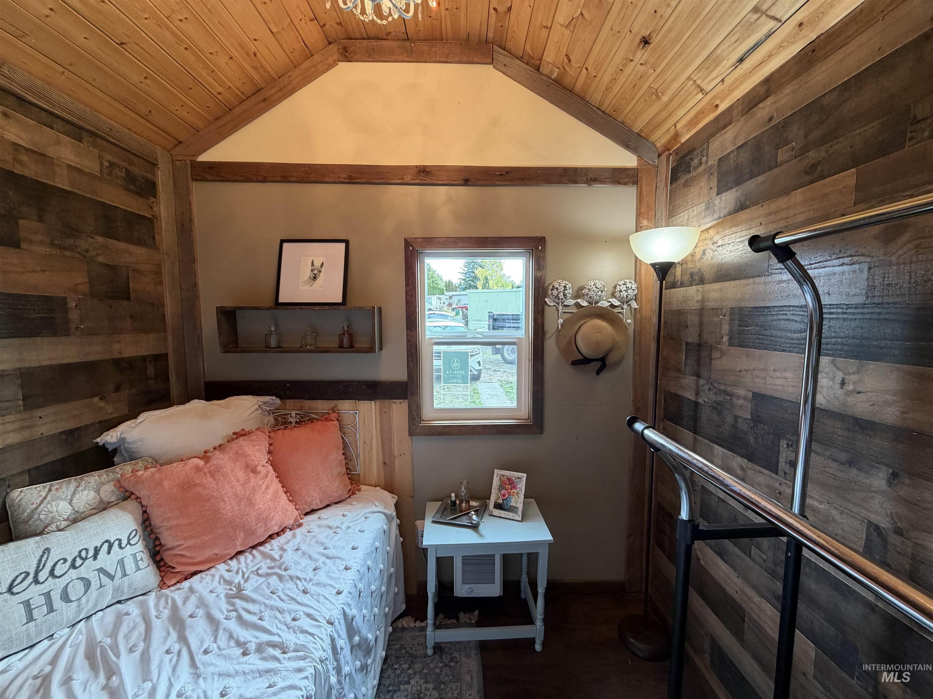 Bedroom with wood walls, lofted ceiling, wooden ceiling, and dark wood finished floors
