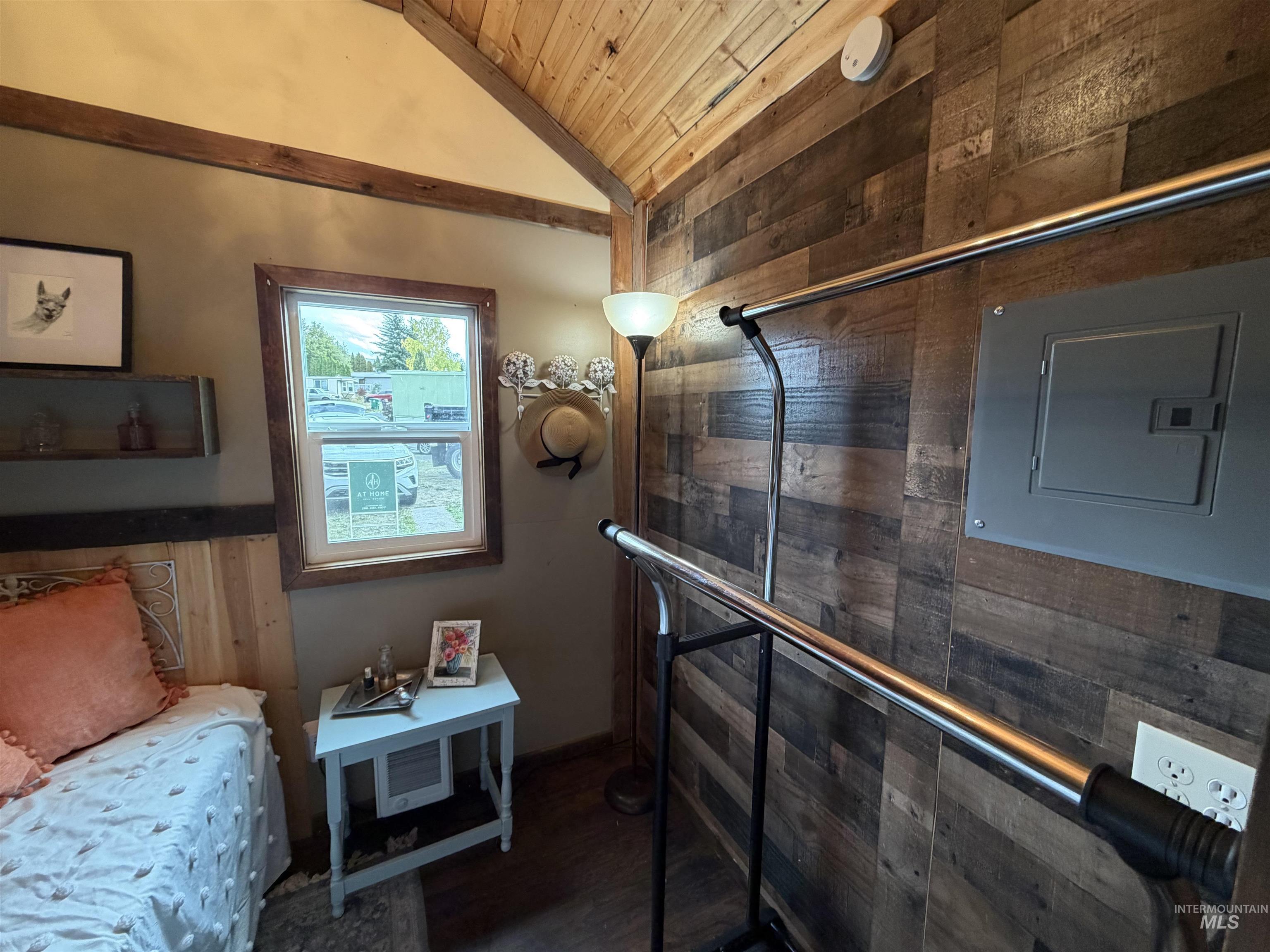Interior space featuring wooden walls, wood ceiling, dark wood-type flooring, lofted ceiling, and electric panel
