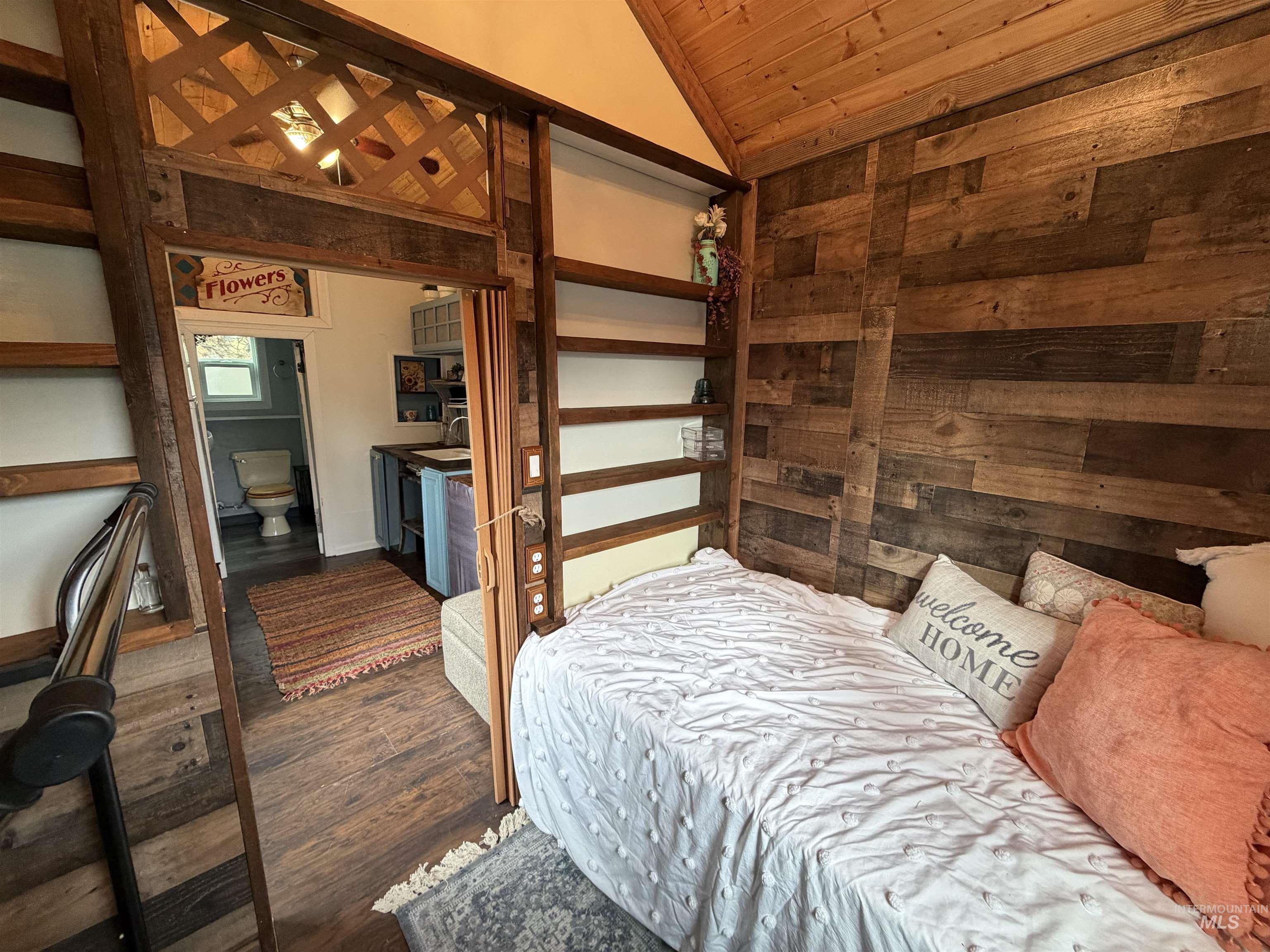 Bedroom featuring lofted ceiling, dark wood-style flooring, wooden ceiling, and wood walls