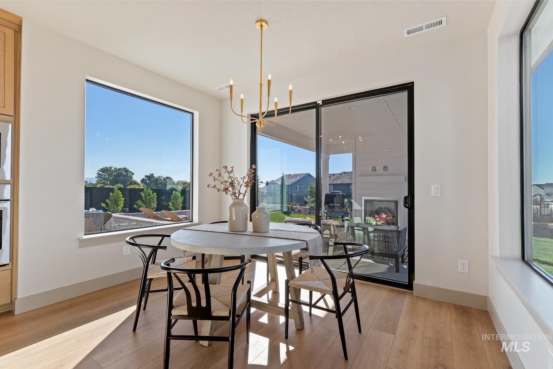 Dining area with a chandelier, light wood-style floors, and healthy amount of natural light