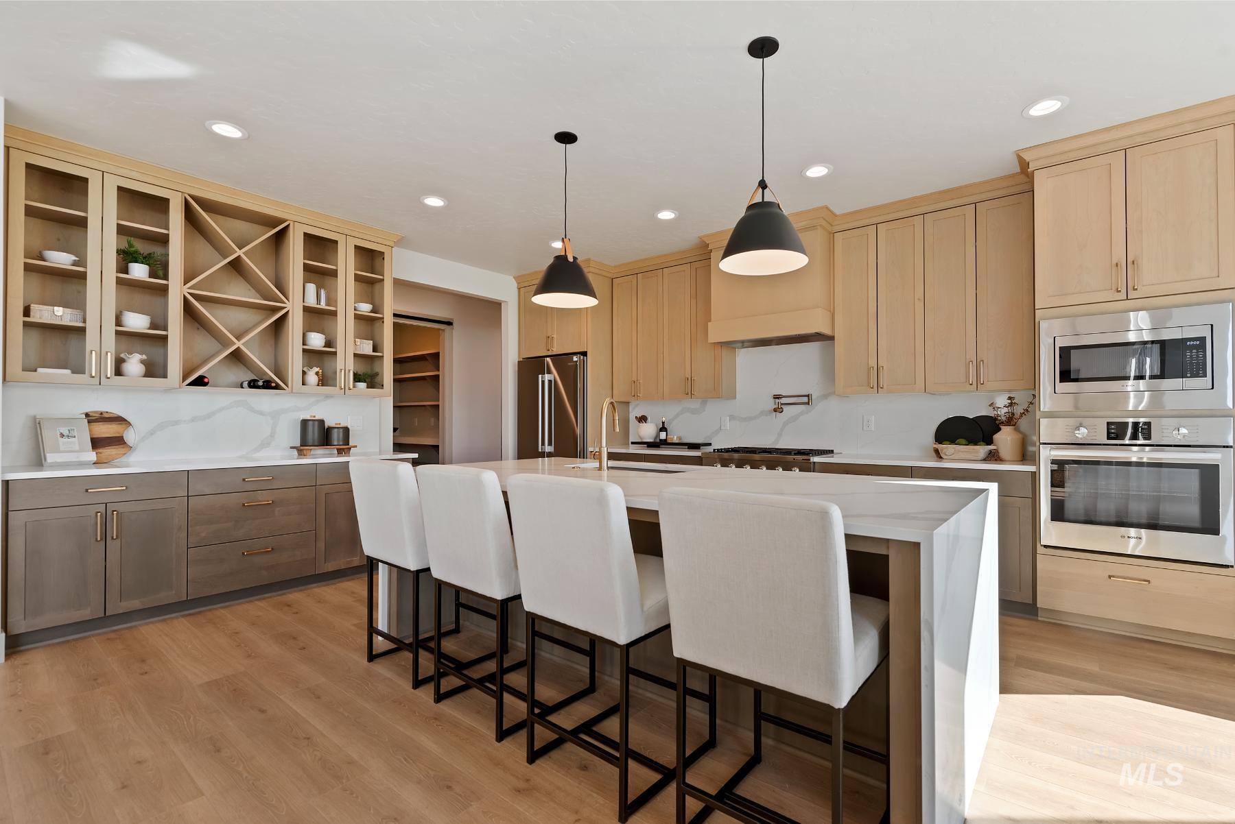 Kitchen with stainless steel appliances, light stone countertops, a kitchen island with sink, light brown cabinetry, and recessed lighting