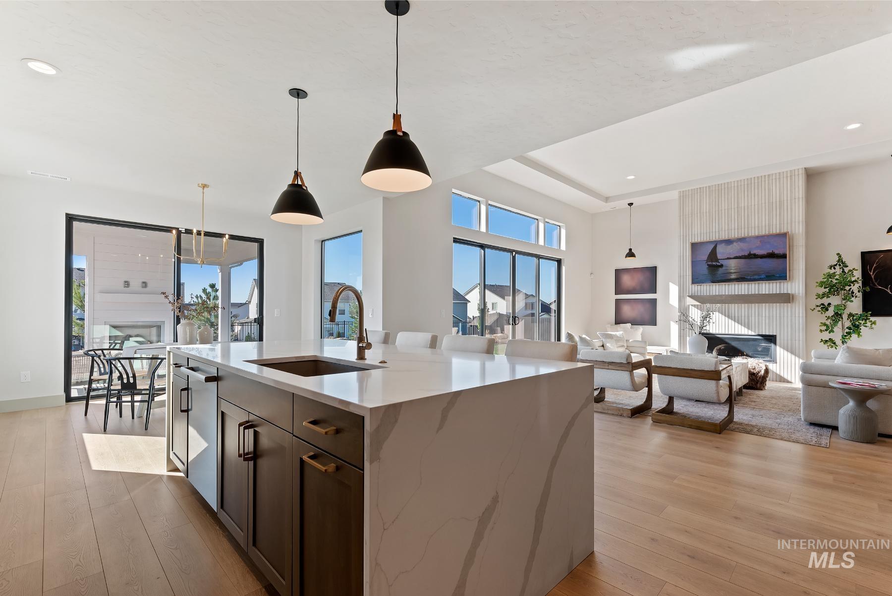 Kitchen featuring open floor plan, hanging light fixtures, light stone counters, recessed lighting, and light wood-style floors