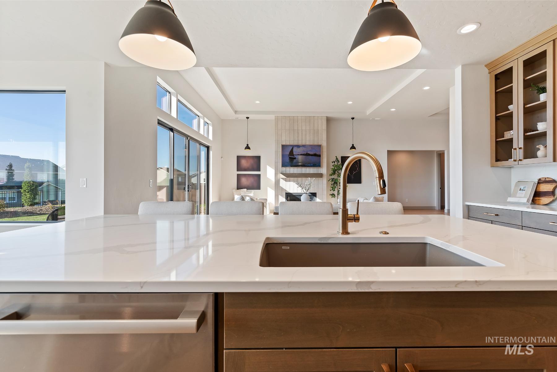 Kitchen with glass insert cabinets, light stone countertops, decorative light fixtures, stainless steel dishwasher, and recessed lighting