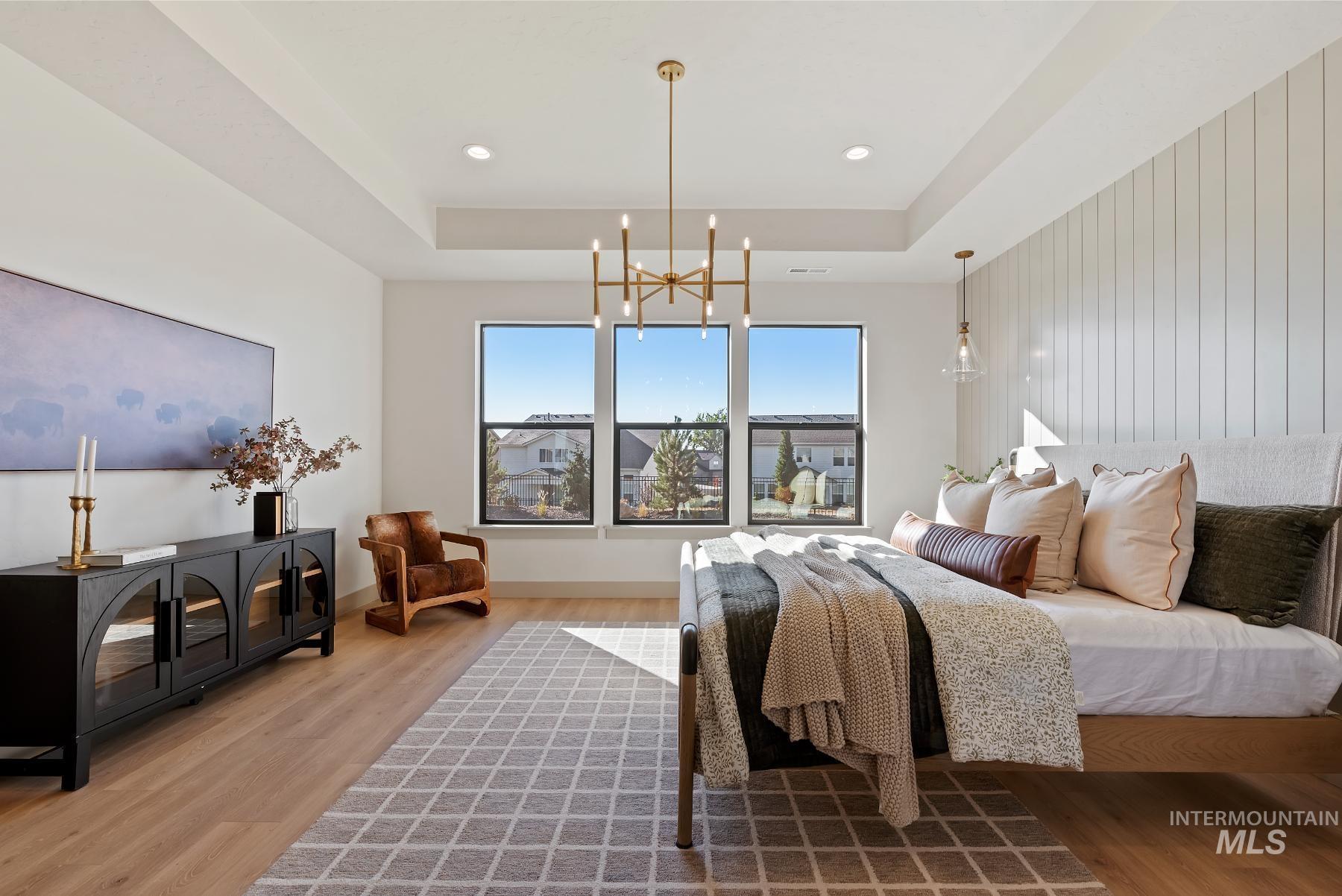 Bedroom featuring a tray ceiling, wood finished floors, a chandelier, and recessed lighting