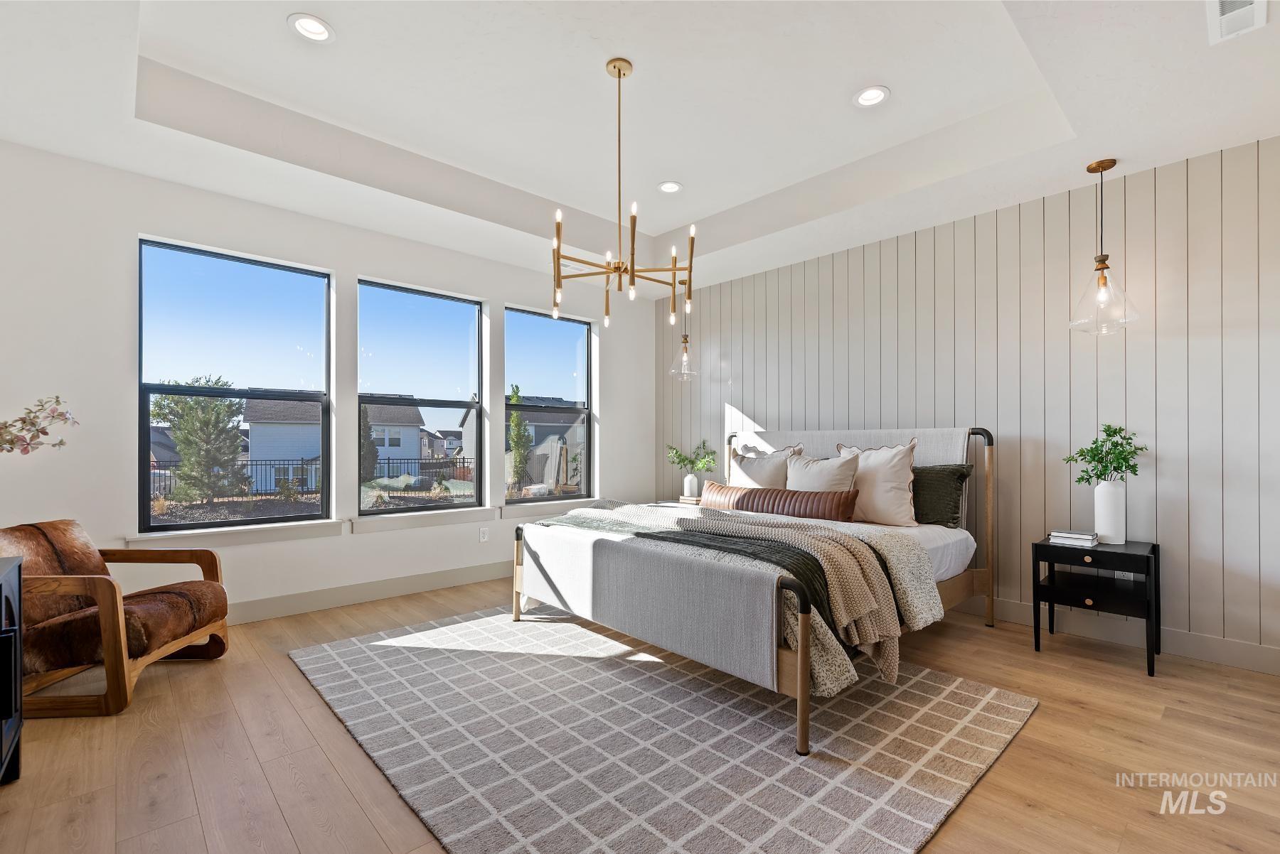 Bedroom with a raised ceiling, a chandelier, light wood-style floors, and recessed lighting