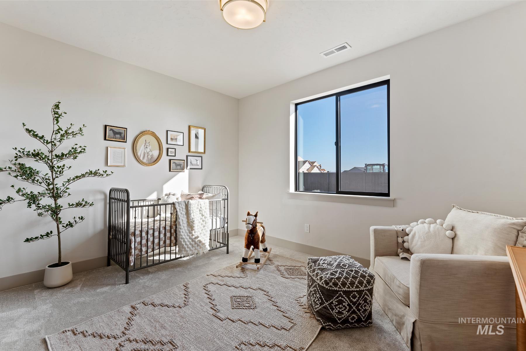 Carpeted bedroom with a crib and baseboards