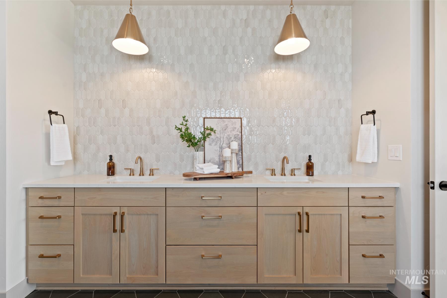 Bathroom with double vanity, decorative backsplash, and dark tile patterned floors