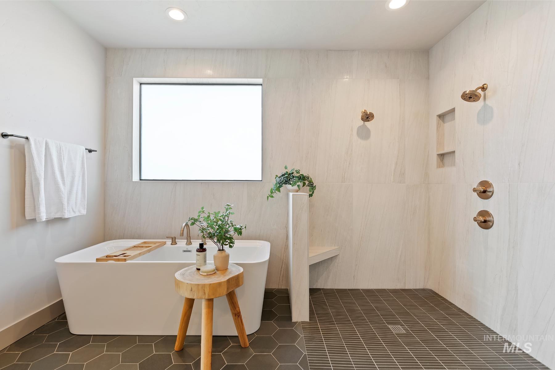 Bathroom with a freestanding tub, dark tile patterned floors, recessed lighting, and a tile shower