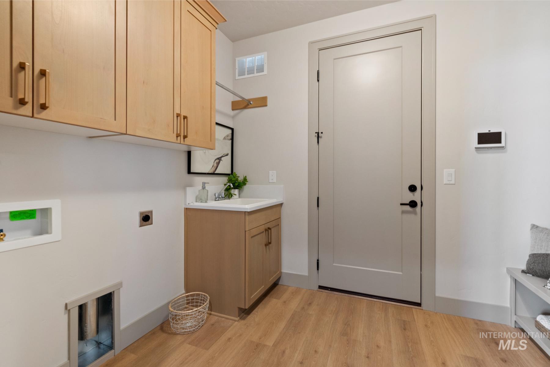 Laundry area with light wood-style floors, cabinet space, electric dryer hookup, and washer hookup