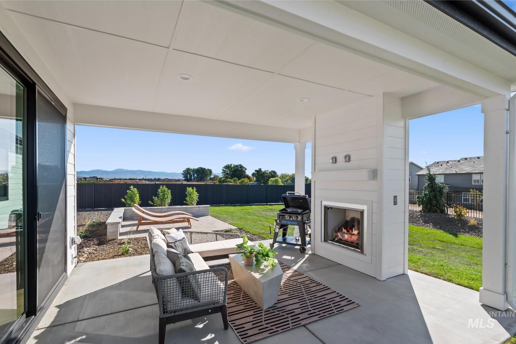 Fenced backyard with a patio, an outdoor living space with a fireplace, grilling area, and a mountain view