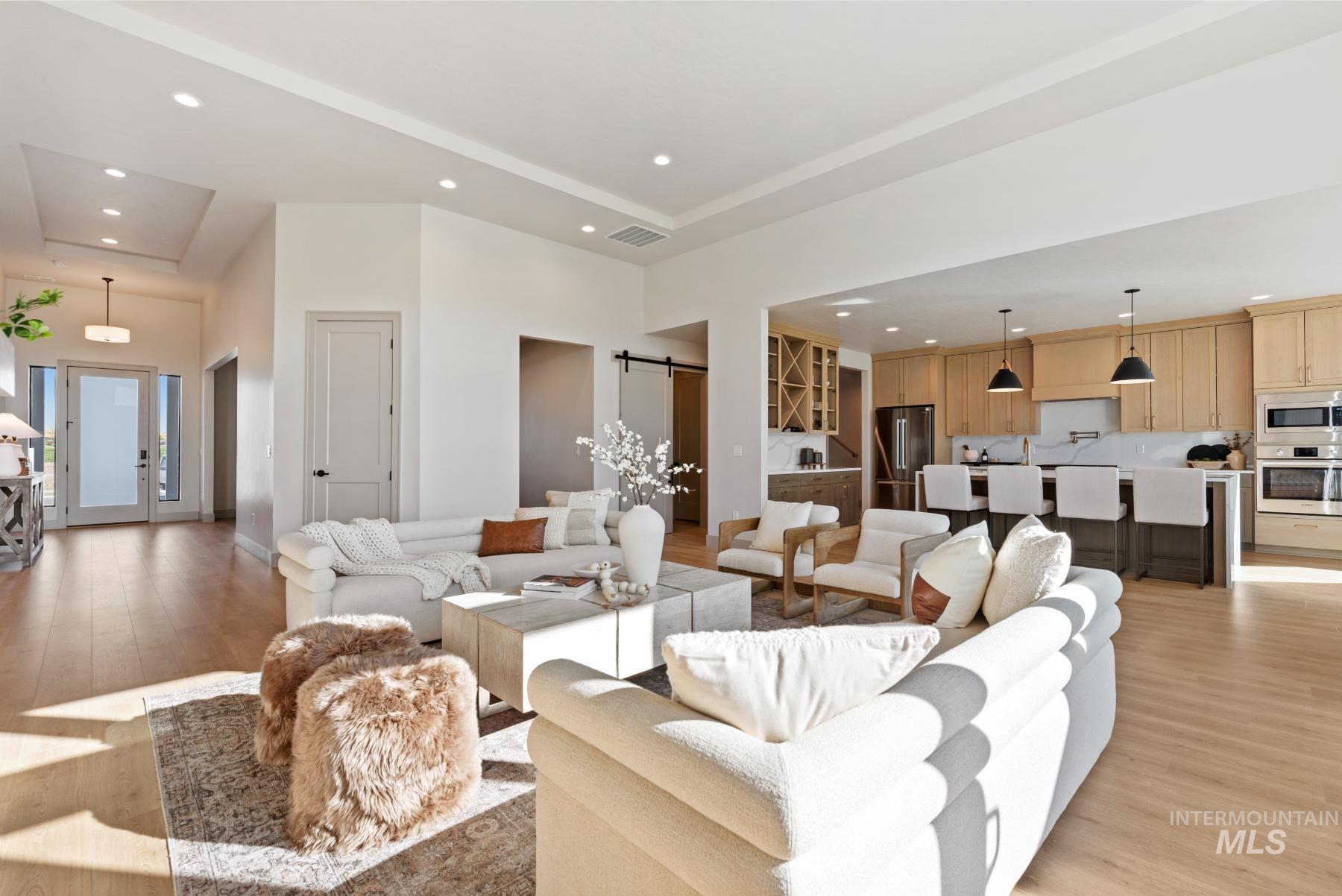 Living room with recessed lighting, light wood-type flooring, a barn door, french doors, and a tray ceiling