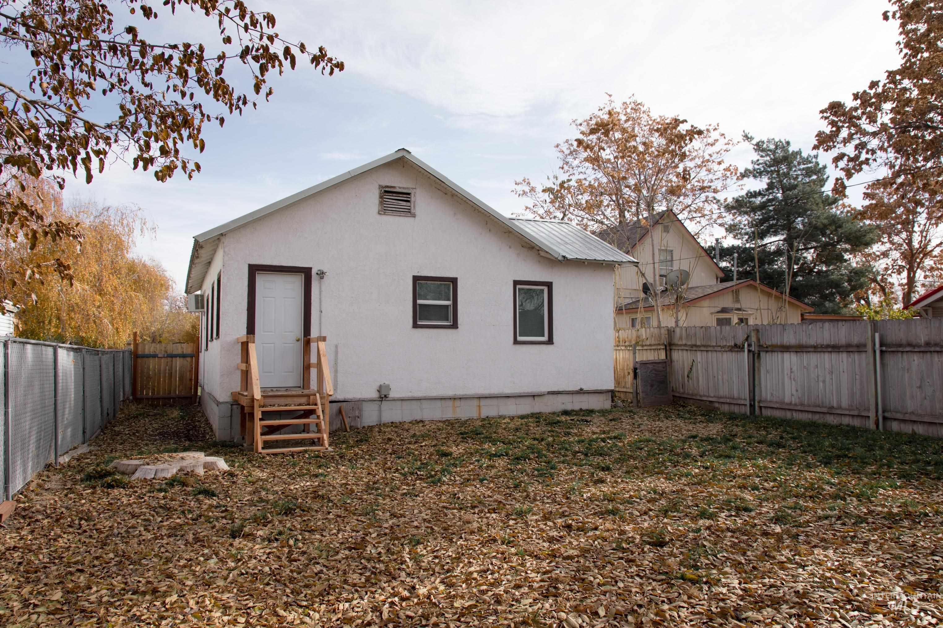 Rear view of house with a fenced backyard, a metal roof, entry steps, and a wall mounted air conditioner