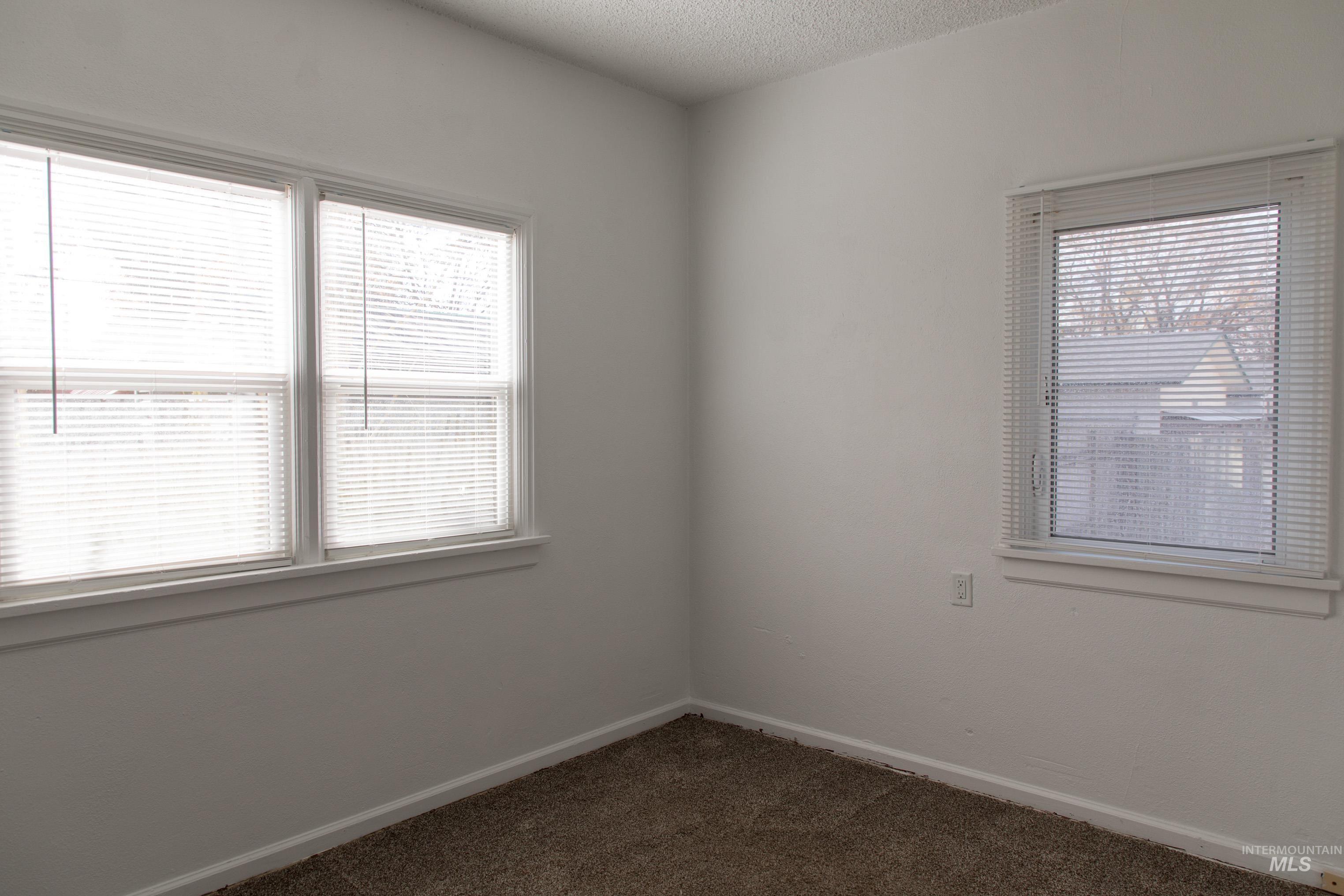Unfurnished room featuring dark colored carpet and a textured ceiling