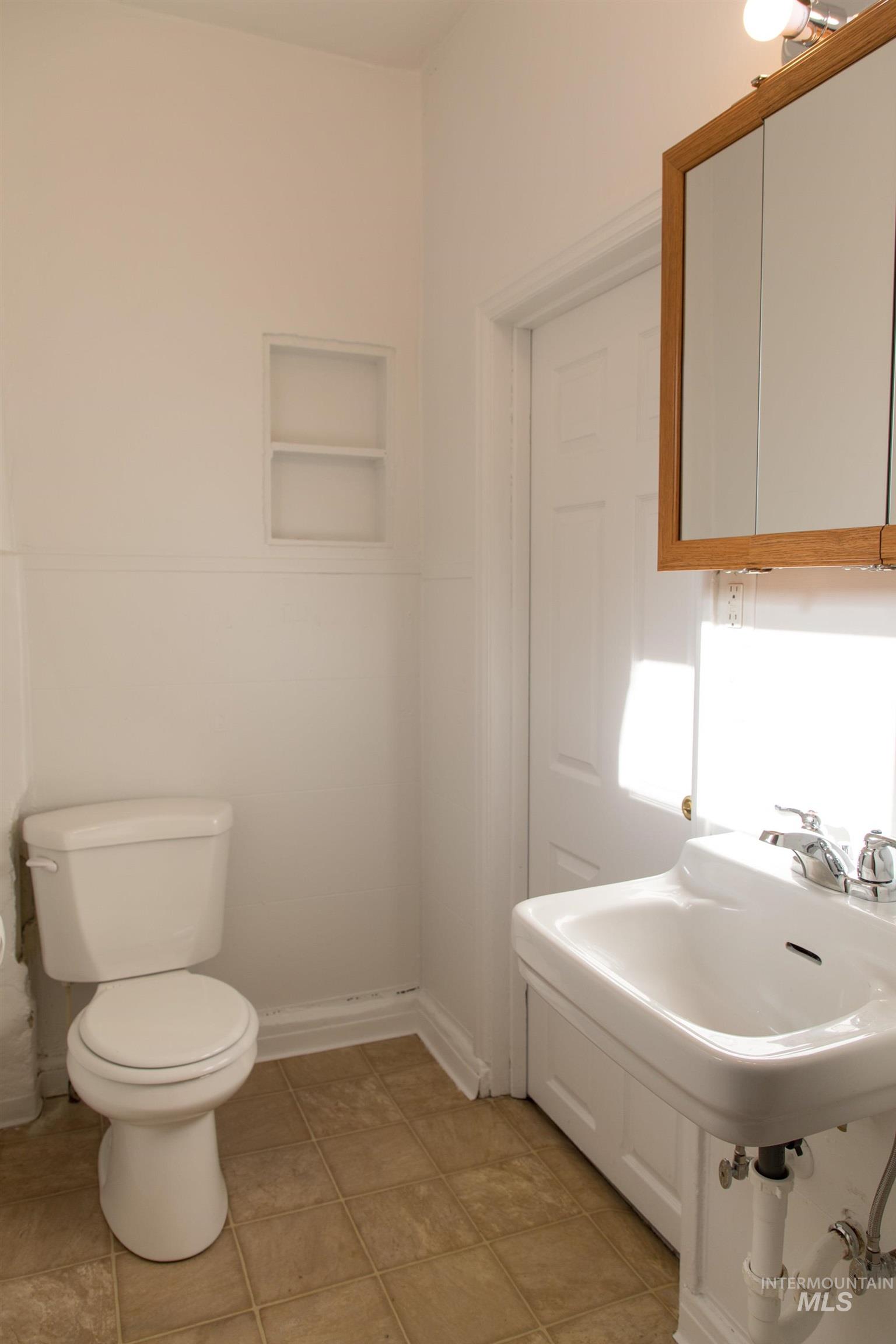 Half bathroom with toilet and light tile patterned floors